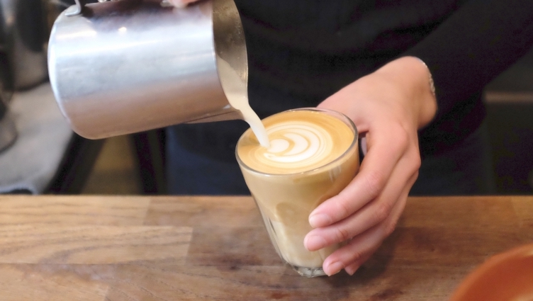A latte being poured at speciality coffee shop Alchemy Cafe in London