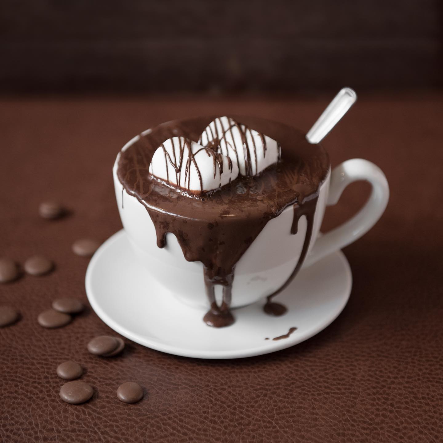 A cup of hot chocolate with chocolate oozing over the edge.
