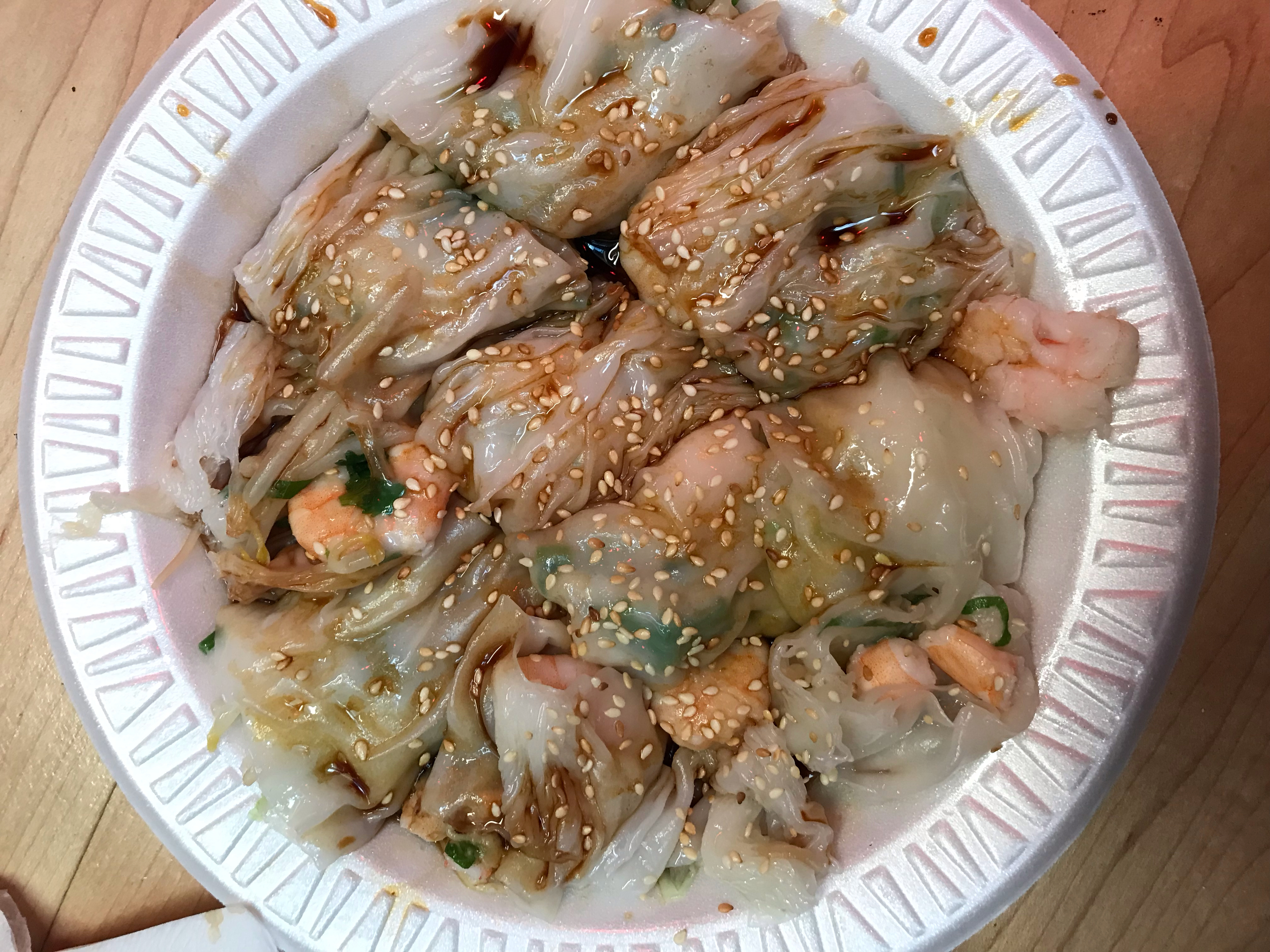 A white styrofoam plate with rice noodle and shrimp rolls