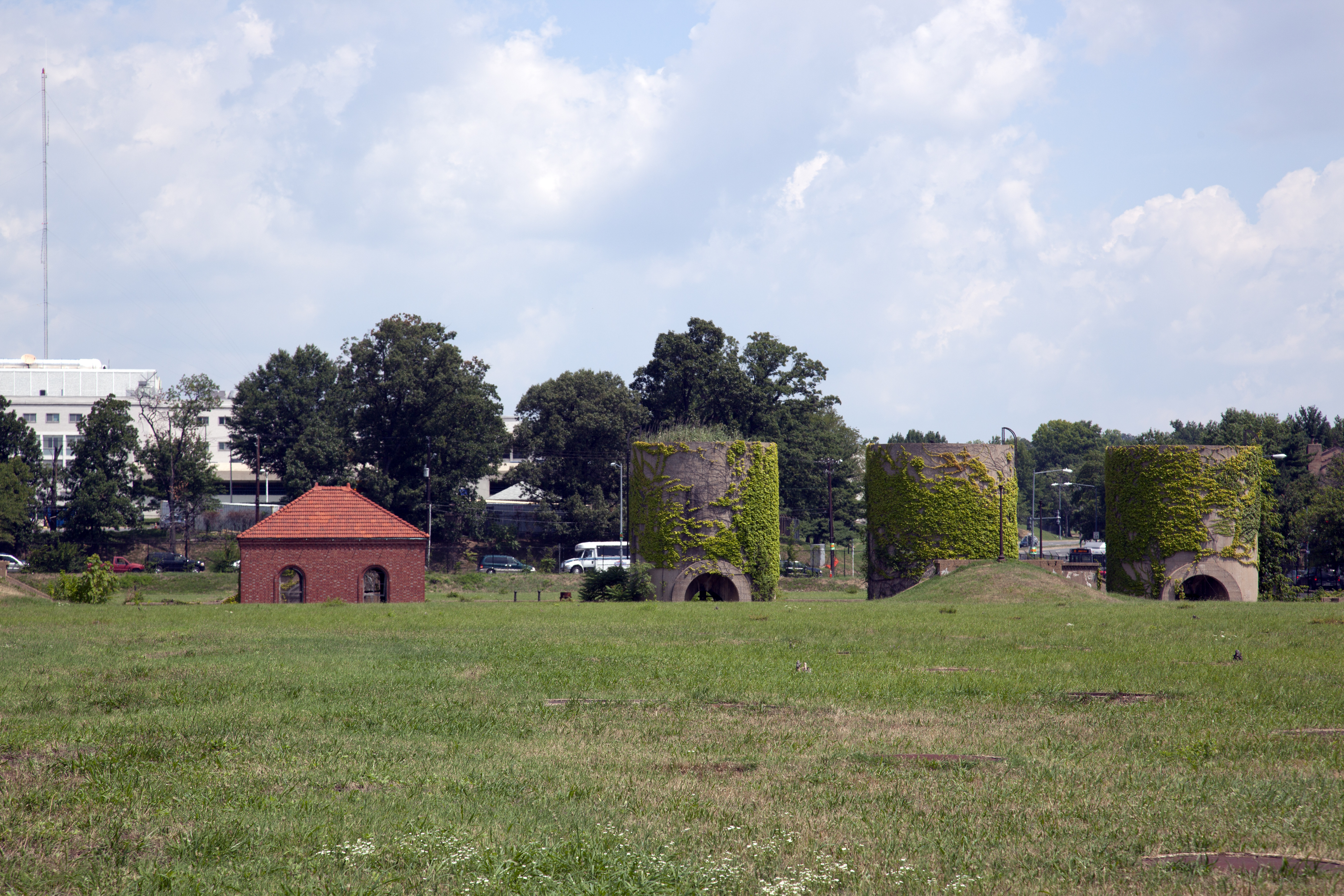 A set of sand silos in the middle of a green field.