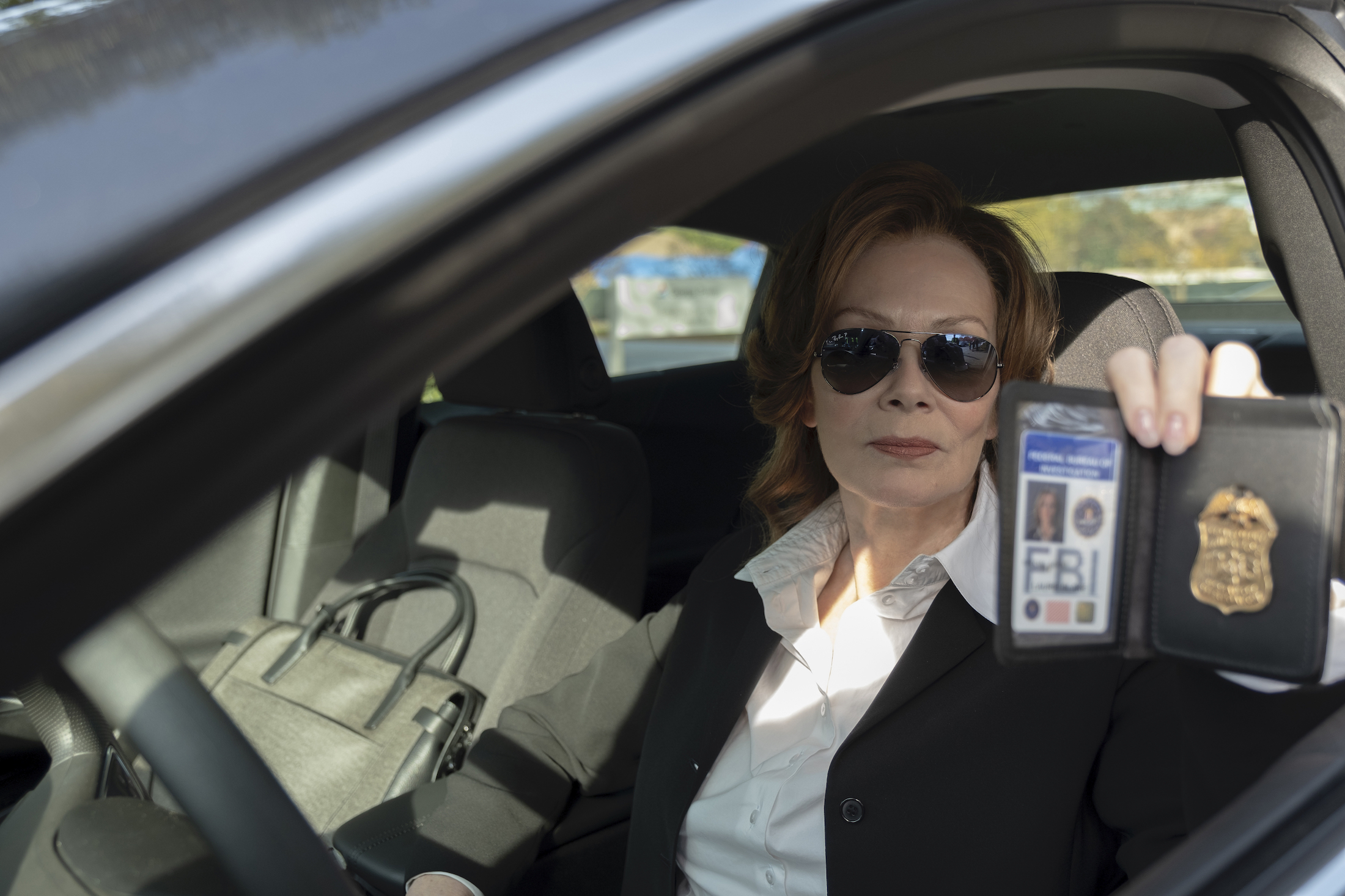 laurie (jean smart) rides up to the graveyard in shades and flashes her FBI badge