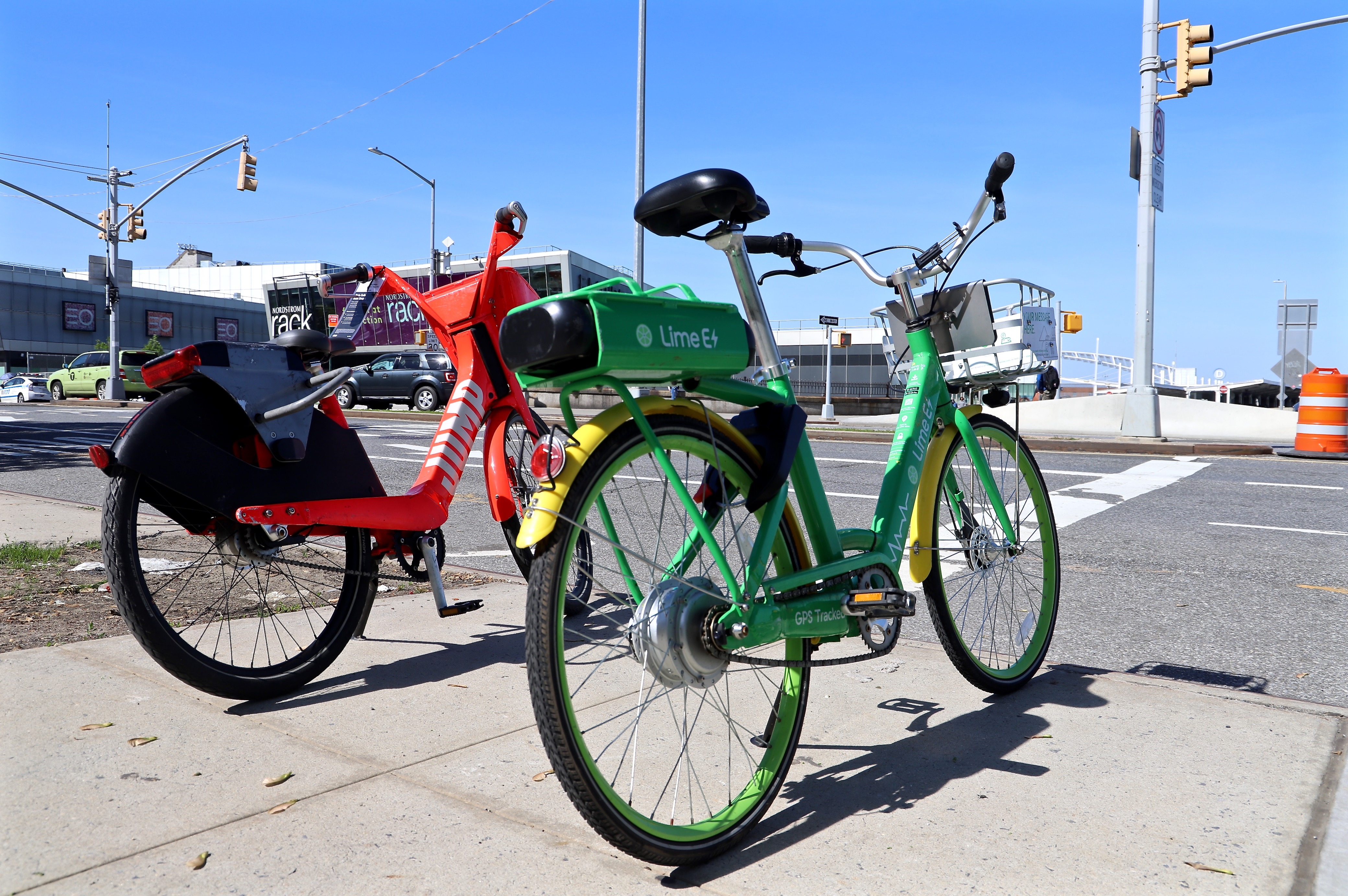 Two bikes, one red one and one green one parked on a sidewalk in Staten Island.
