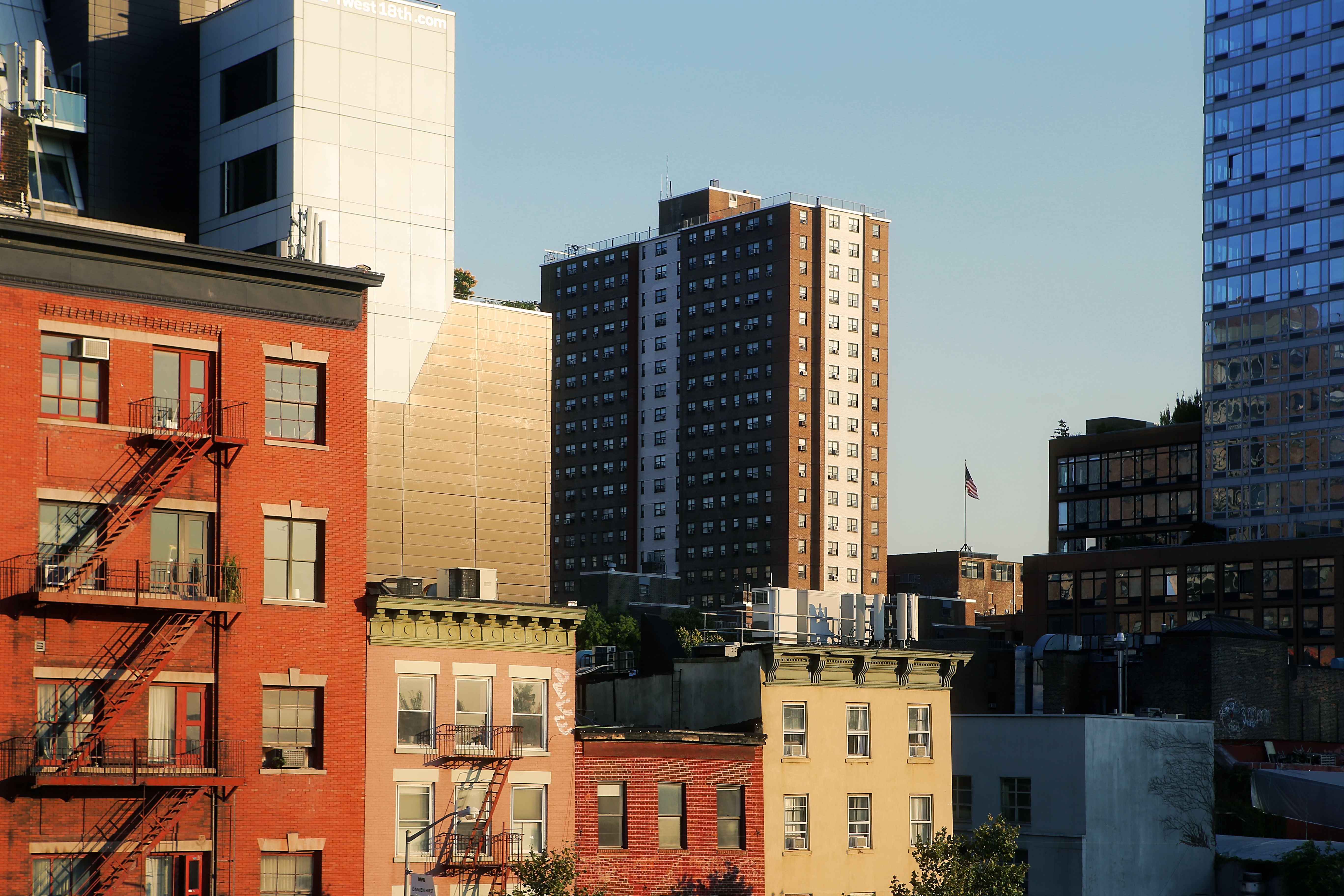 A brown public housing building rises among different residential buildings in New York City.