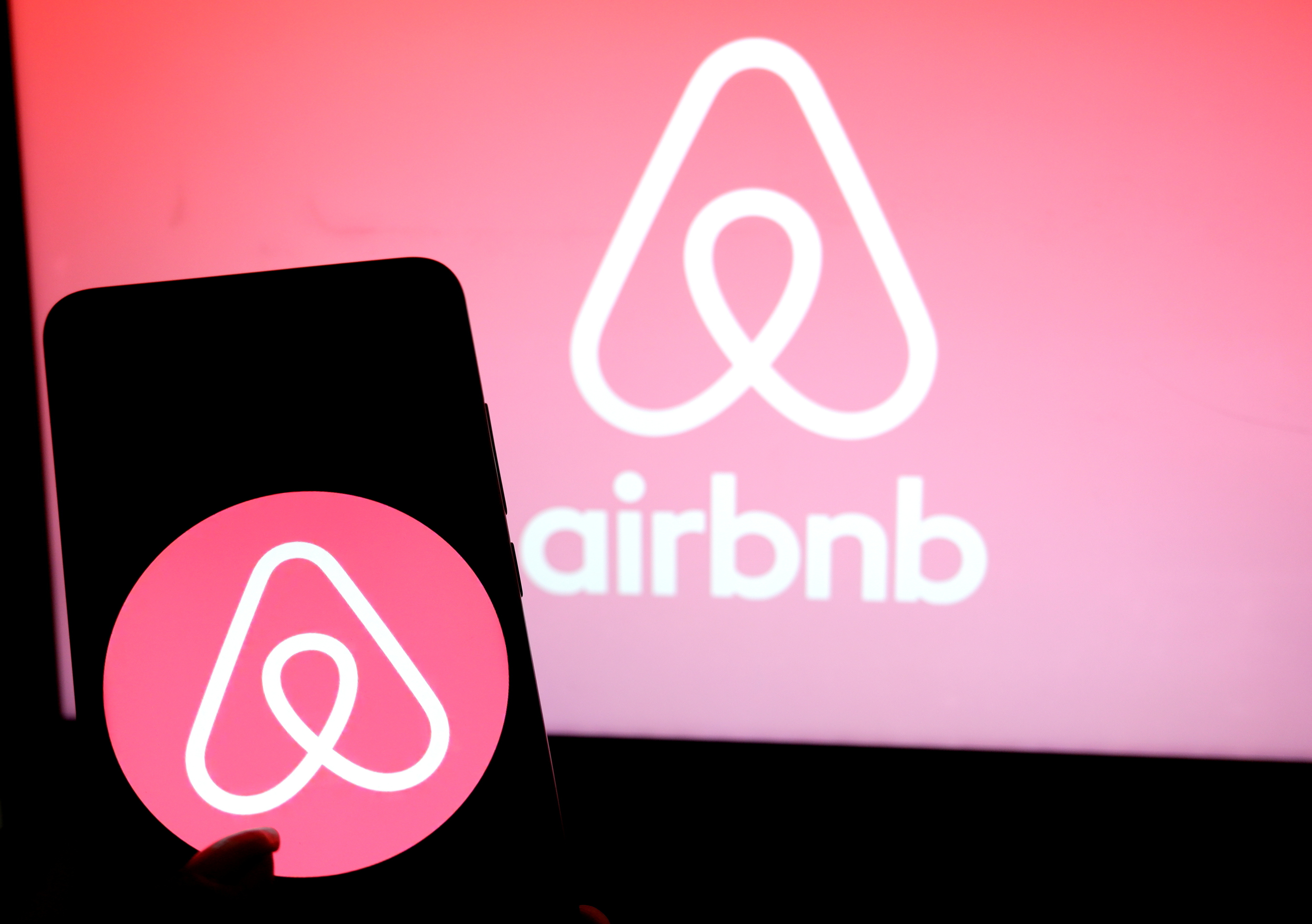 The Airbnb logo is seen displayed on a smartphone.