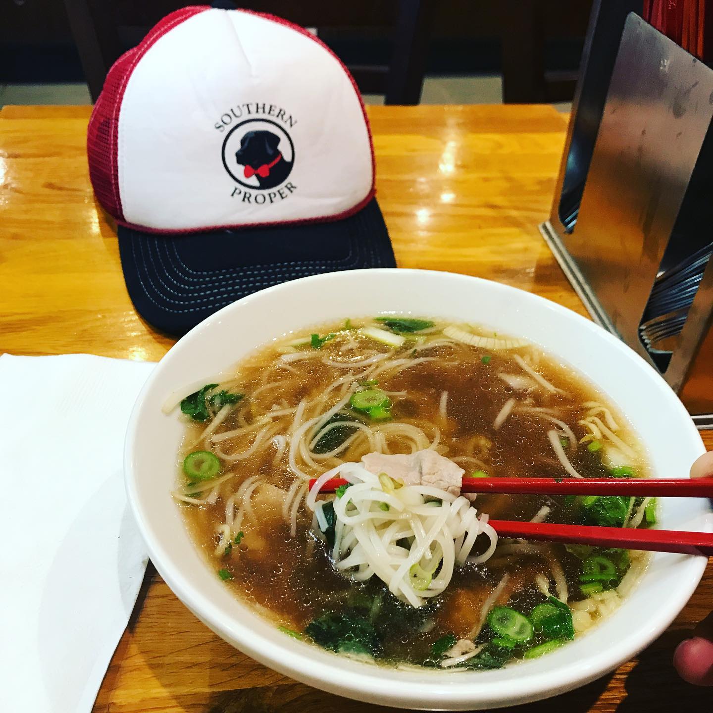 A bowl of pho with chopsticks in it.