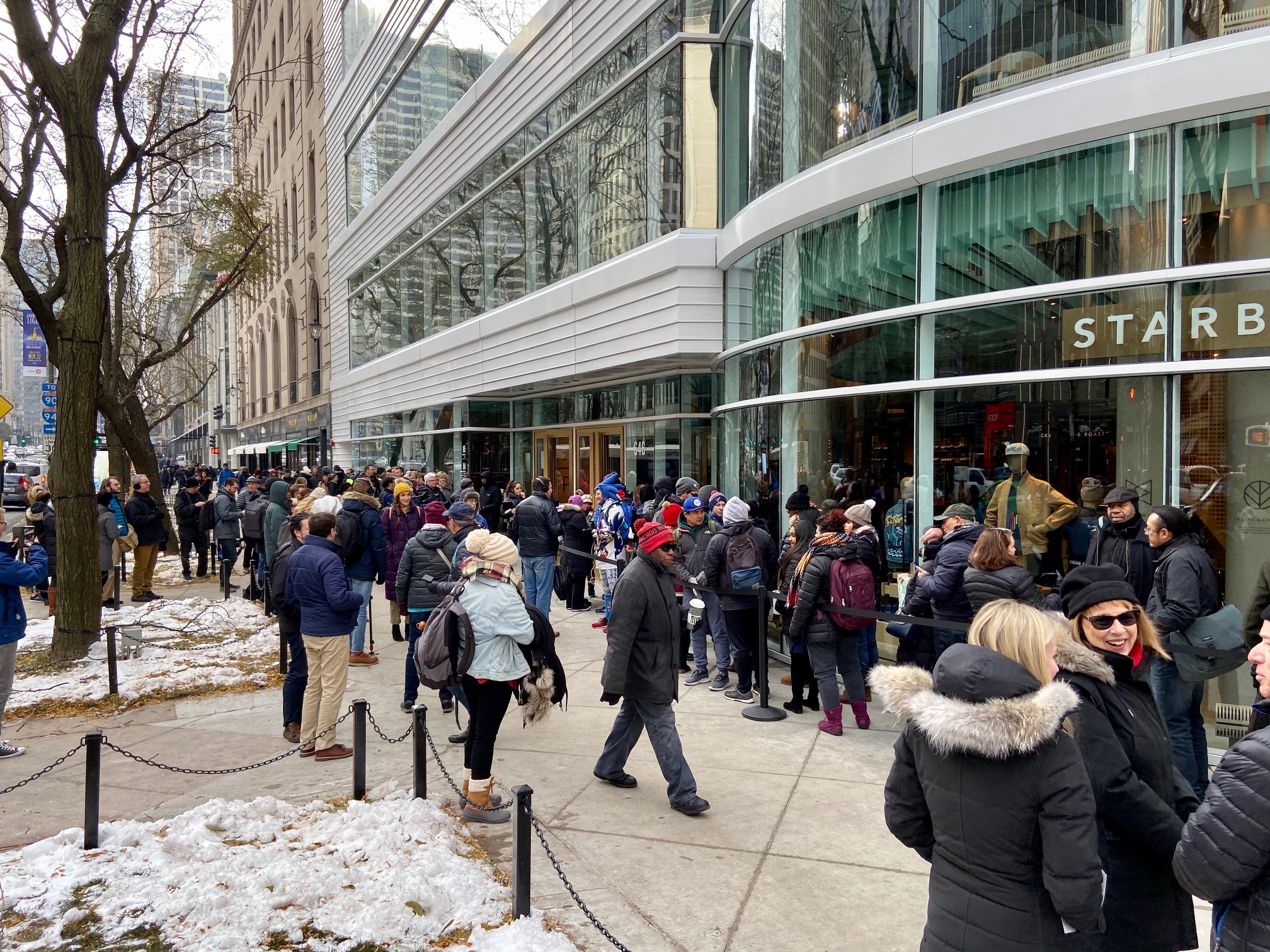 A large crowd of people waiting on the street outside the Starbucks Reserve Roastery in Chicago.