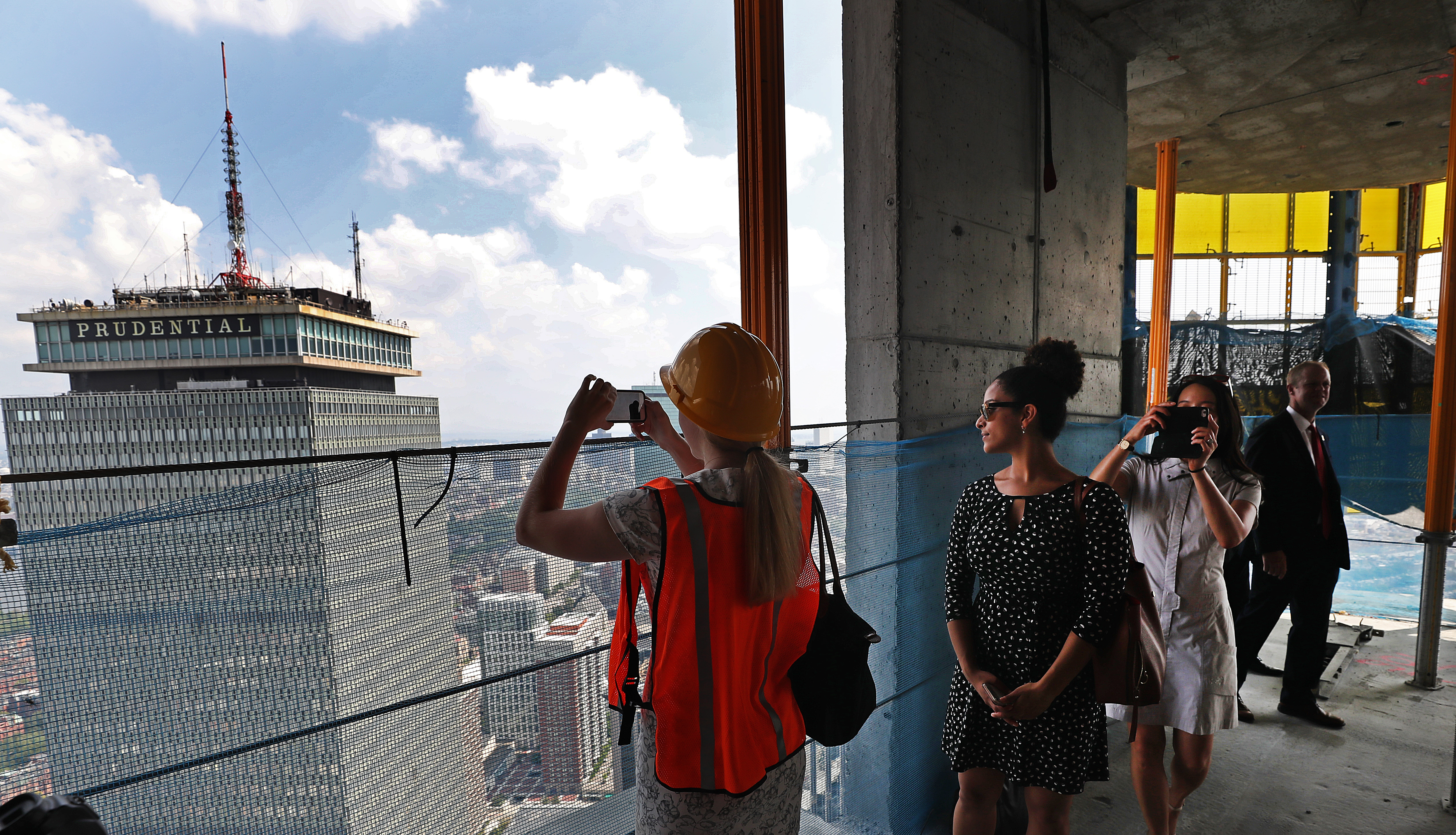 People milling about and snapping photos from an open floor of an under-construction skyscraper.