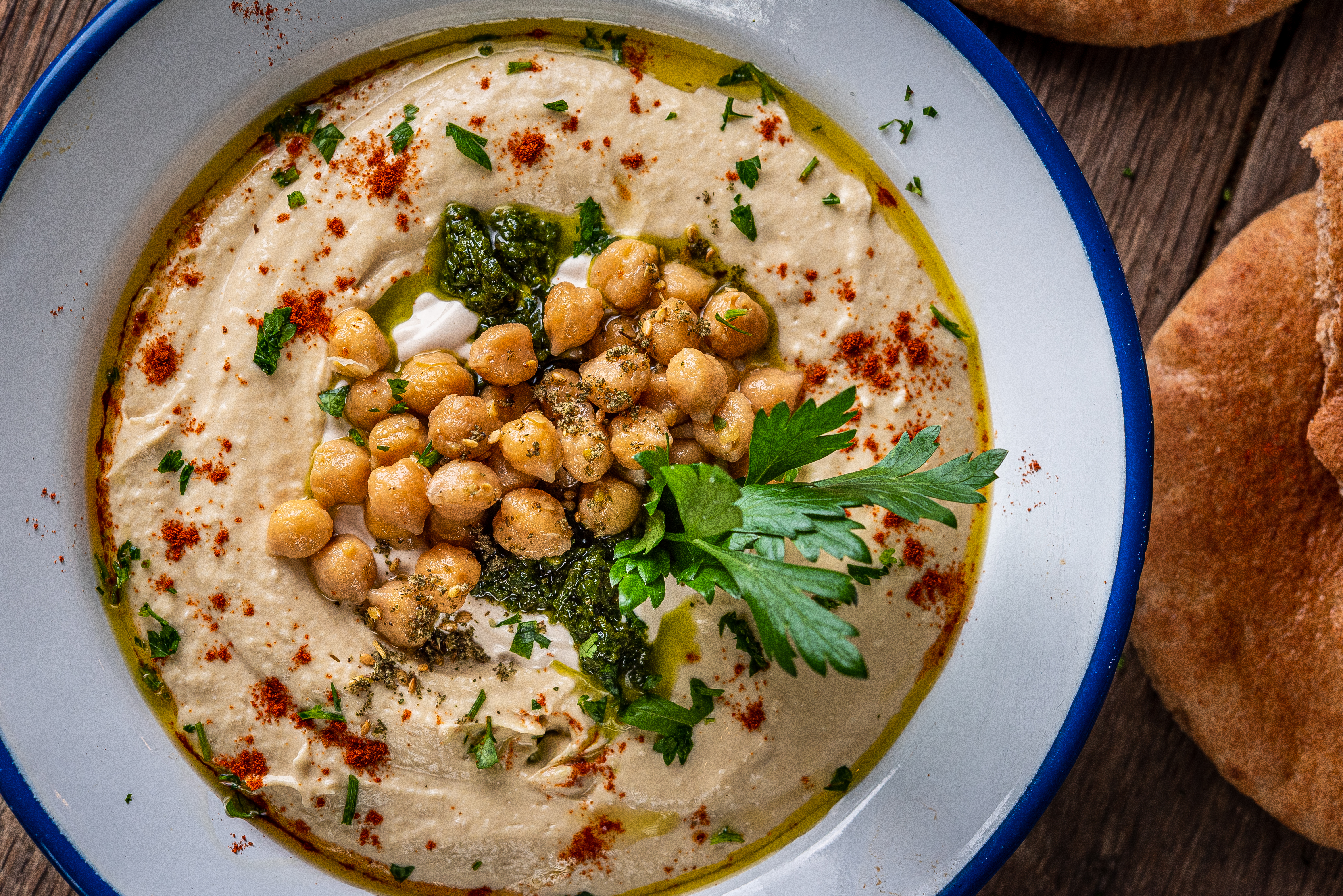 A close-up of a “classic” hummus bowl from Shouk with tahina, chickpeas, za’atar, spices, parsley, and olive oil.