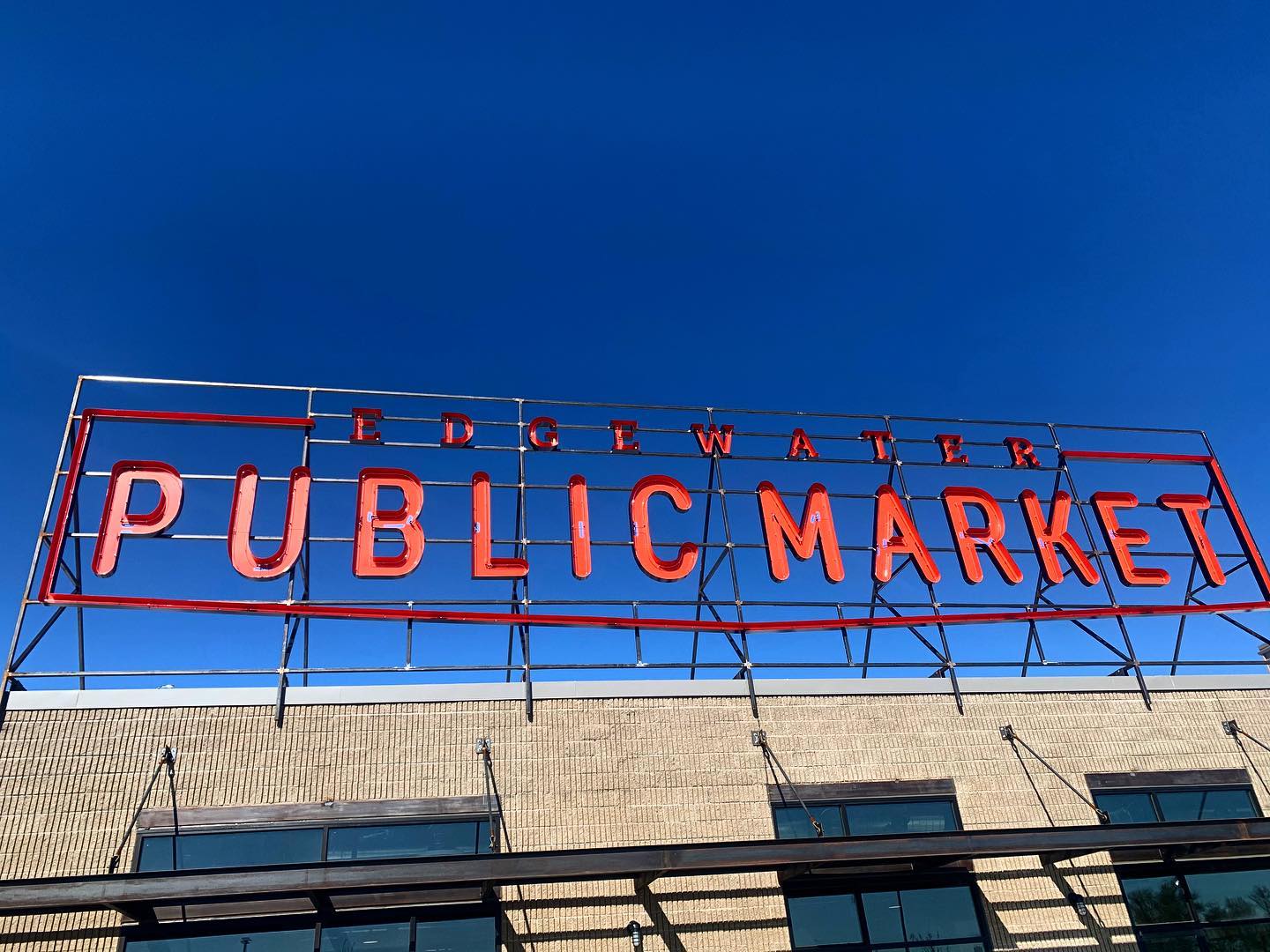 A photo of a sign reading “Edgewater Public Market” in red letters above the market building