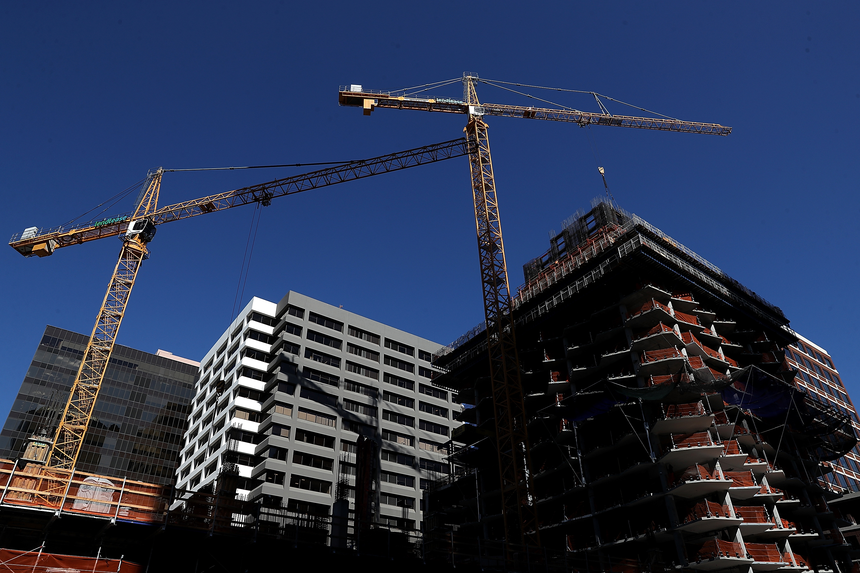 Construction cranes hang over a building under construction.