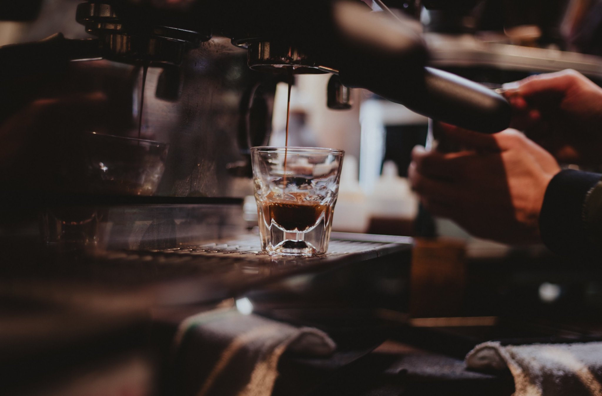 A closeup of a coffee drink being made as a barista works an espresso machine.