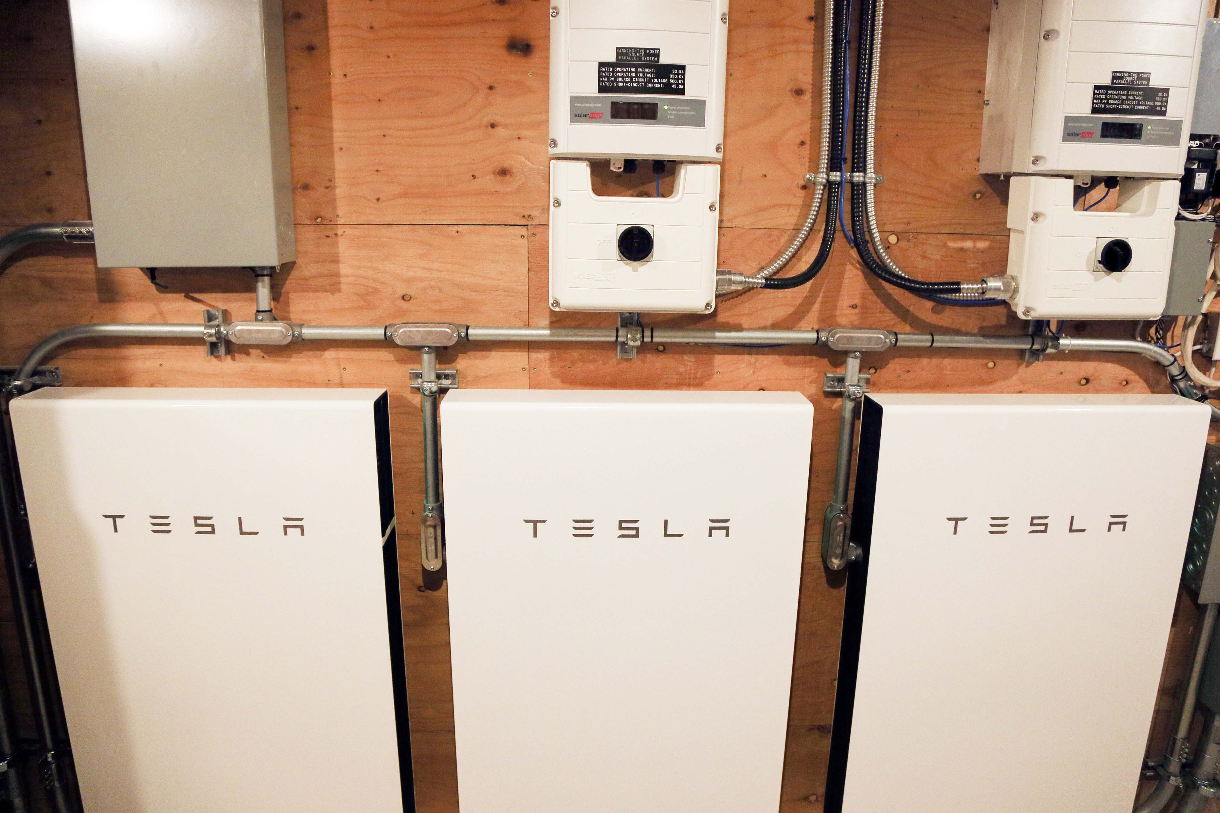 A bank of Tesla batteries on a wall in a home’s garage.