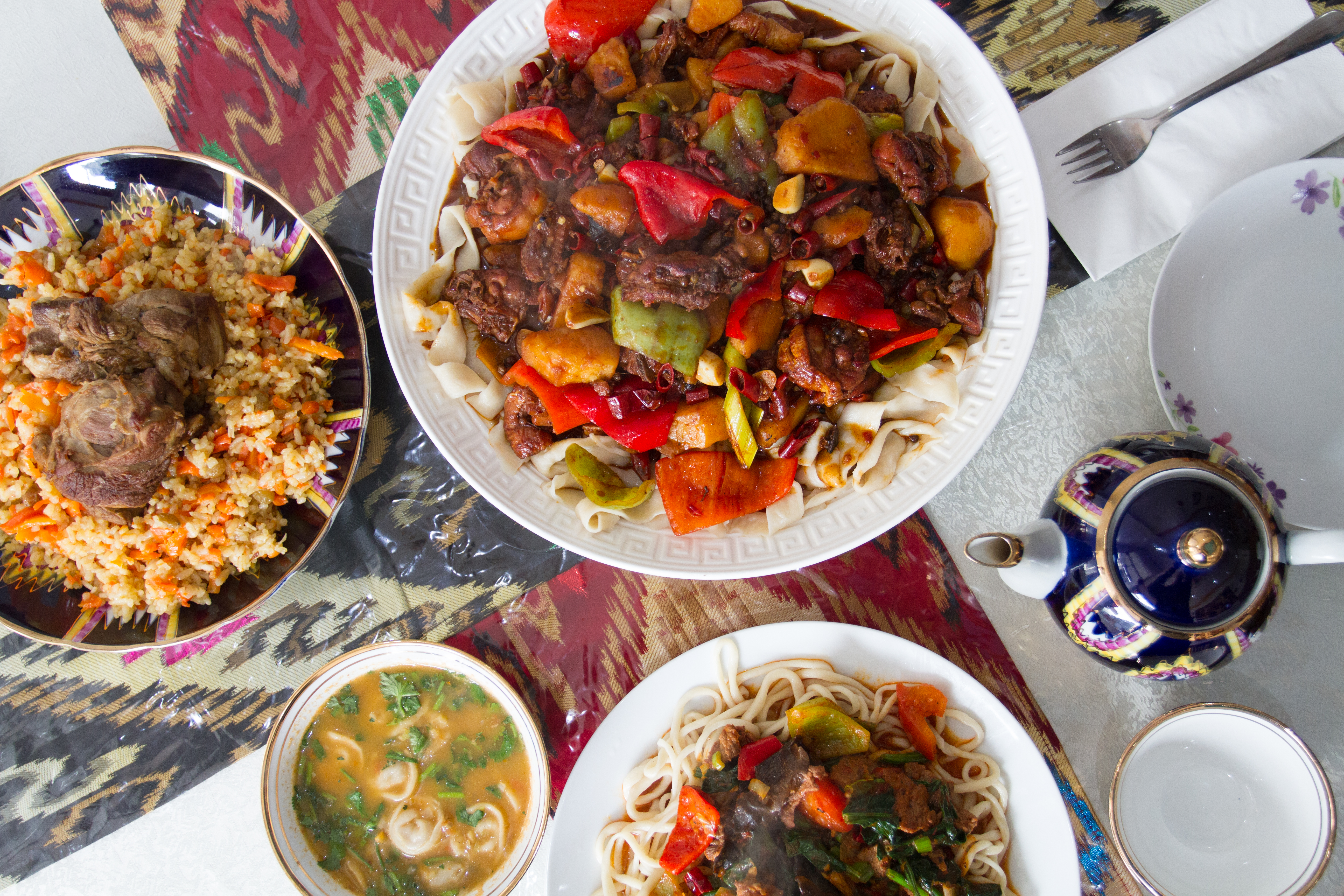 A variety of dishes, including a meat and vegetable platter, rice and noodles, and soup.