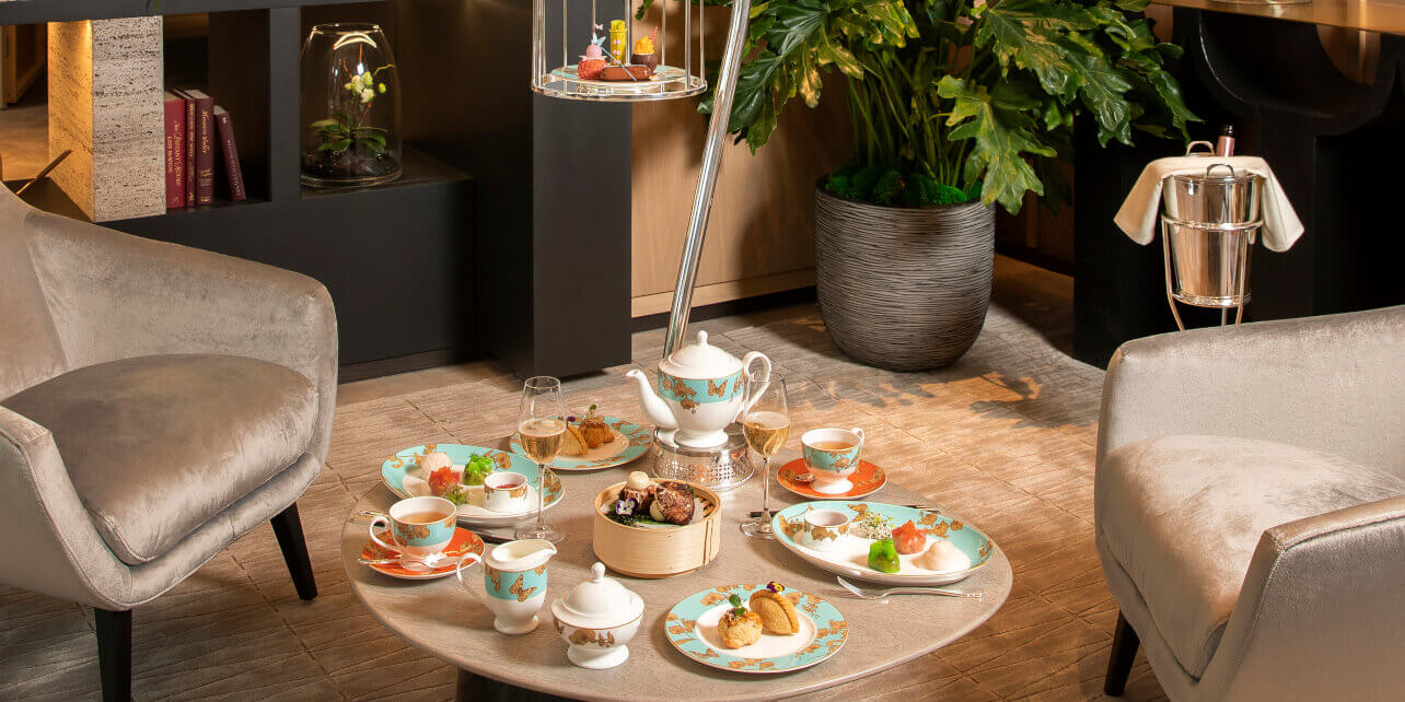 A table set with teal and green afternoon tea crockery. with dim sum and intricate pastries