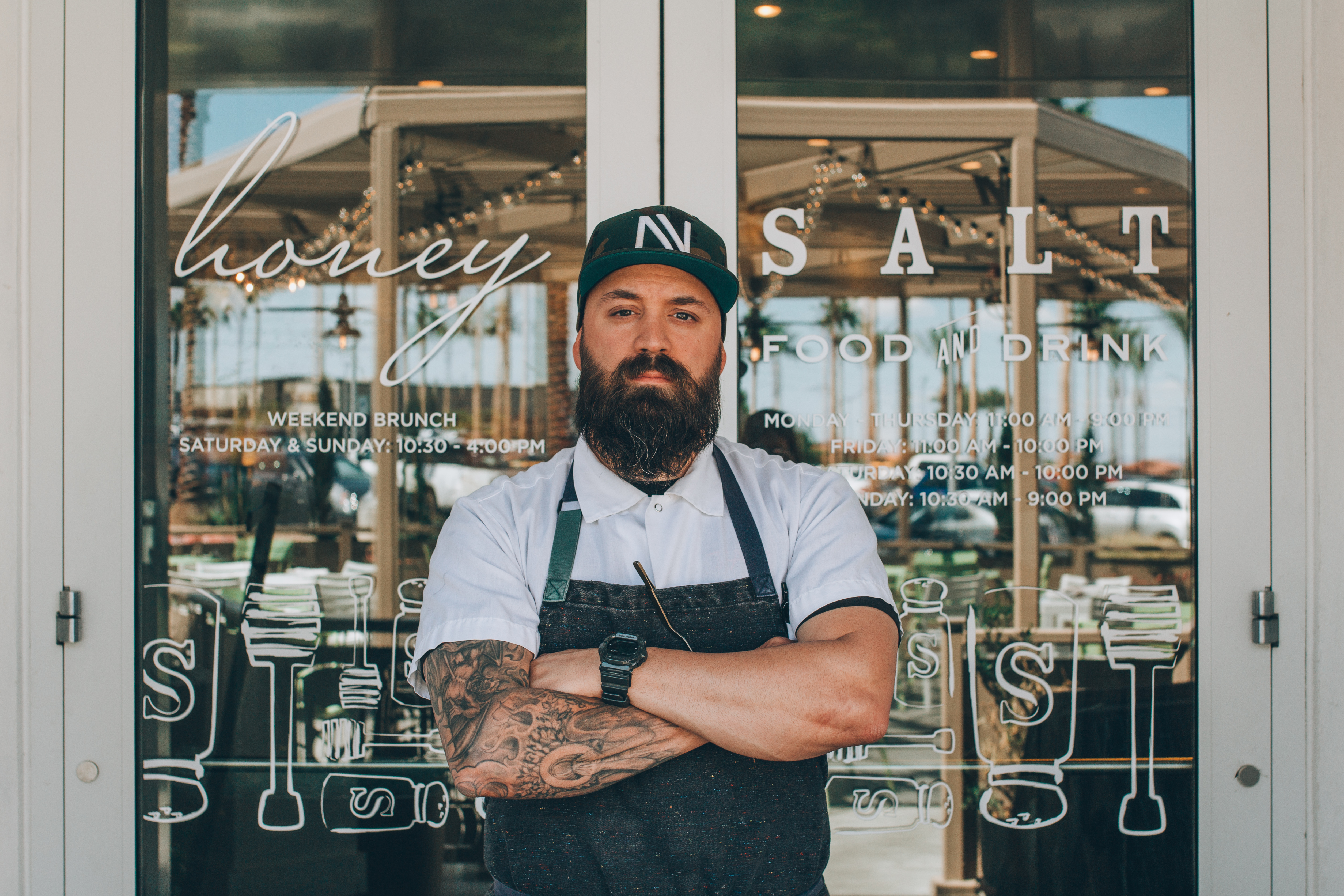 A chef stands with his arms crossed in front of a restaurant