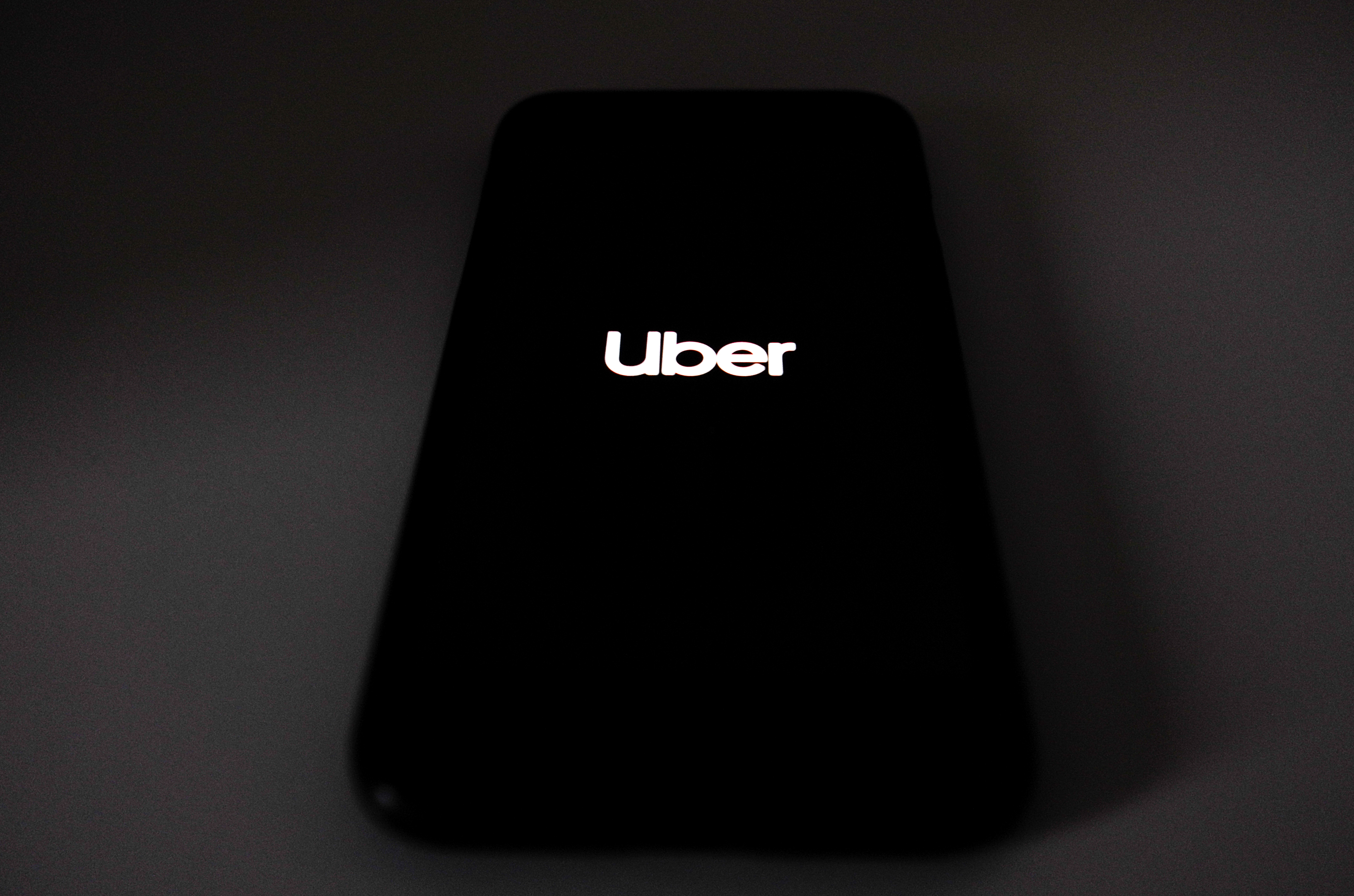 A smartphone screen, in the dark, reading, “Uber.”