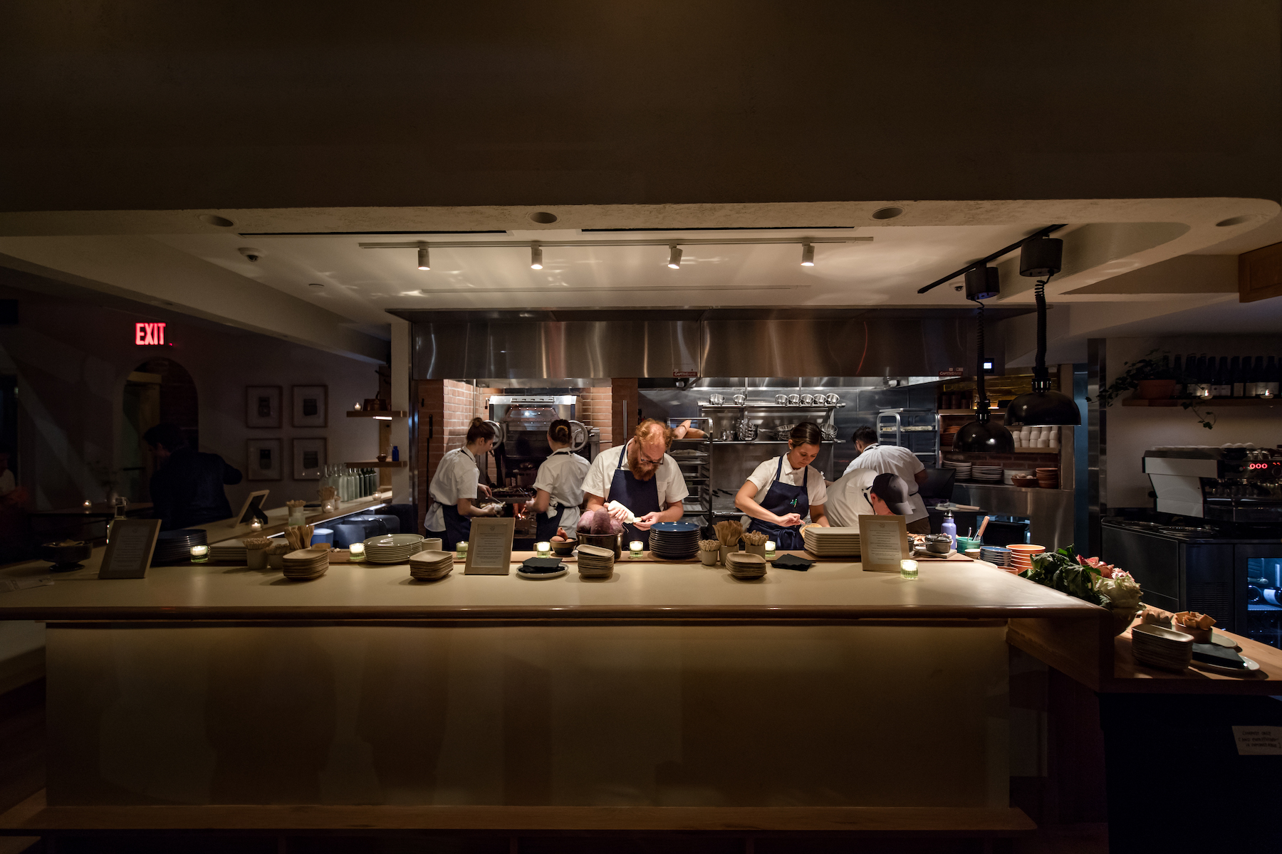 Chefs working behind a gray counter in dark lighting at 232 Bleecker