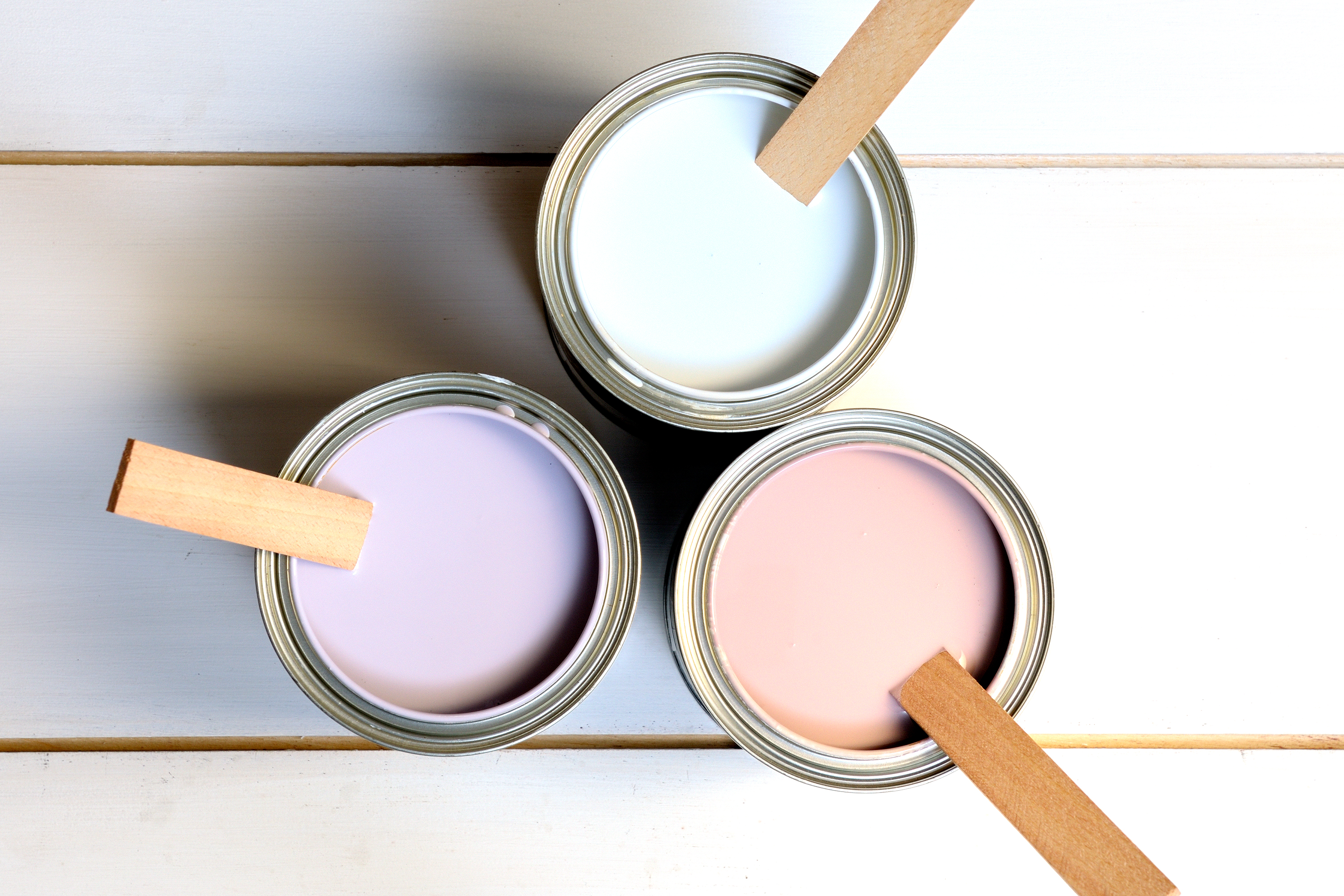 Cans of paint with mixing sticks.