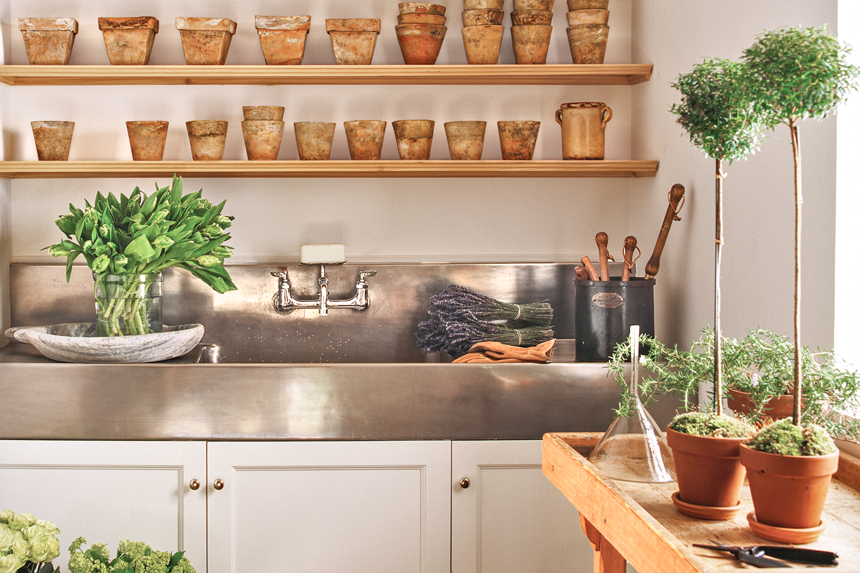 Potting room with a stainless steel sink and terracotta pots on the walls