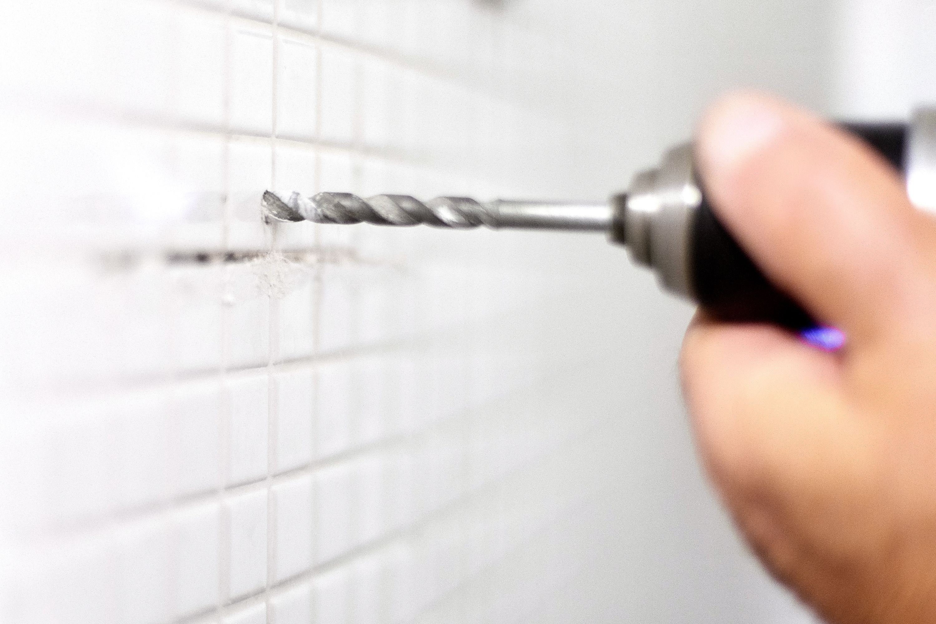 Drilling hole in tile in shower.