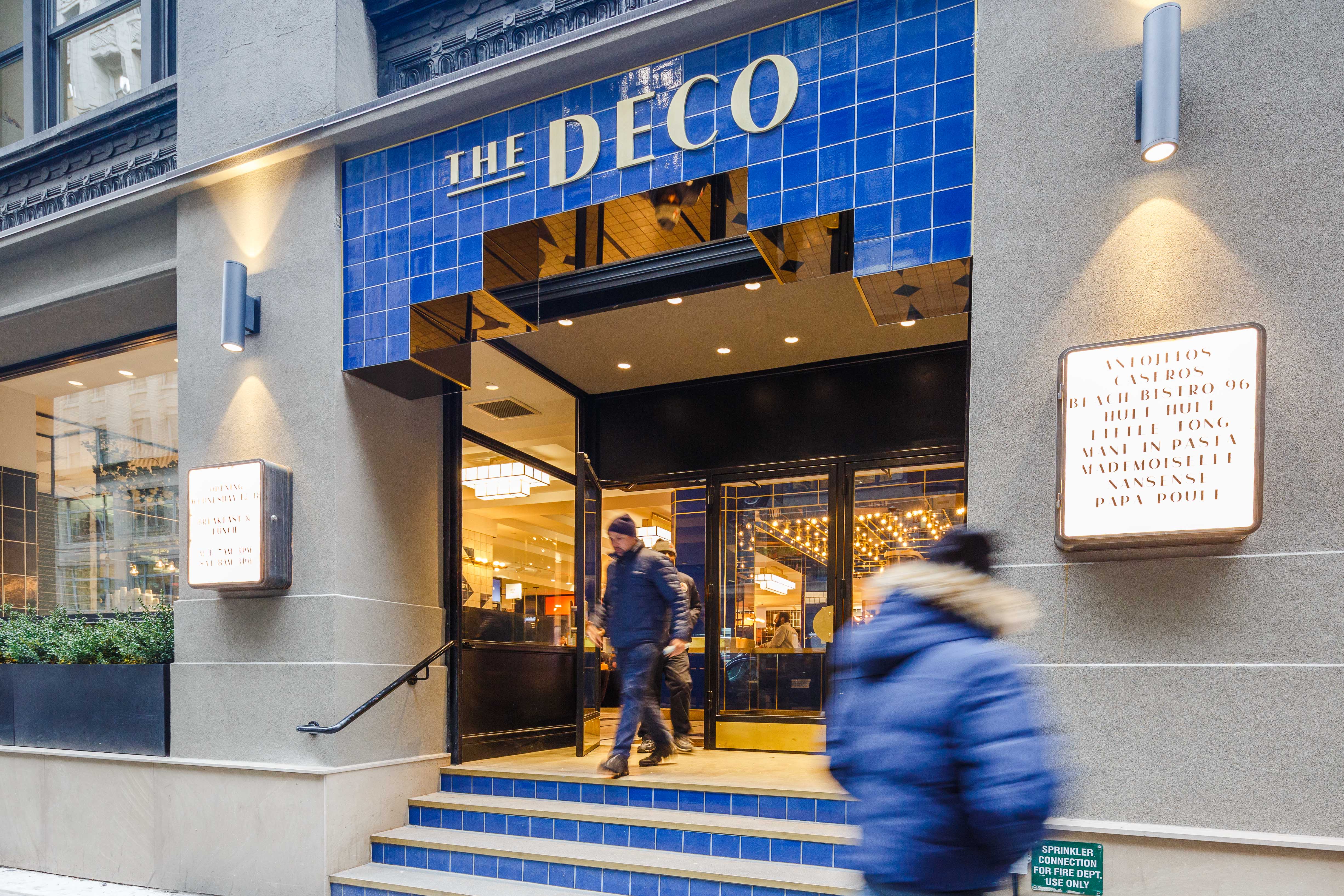 The blue-tiled storefront of the Deco with a sign up top