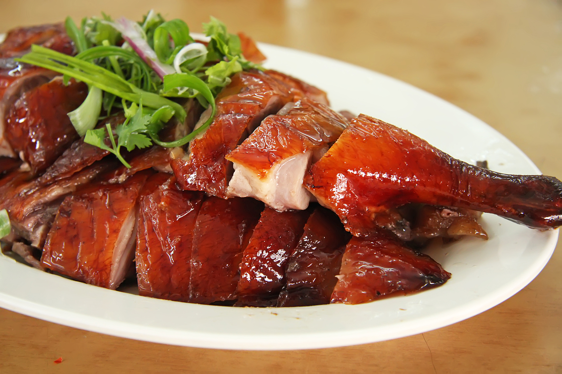 A plate with a whole, sliced crispy Chinese roast duck