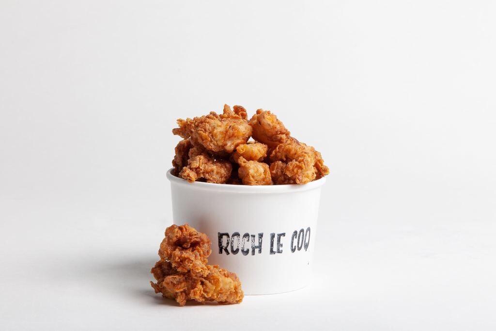 A white paper bucket of fried chicken with Roch Le Coq printed on the front.