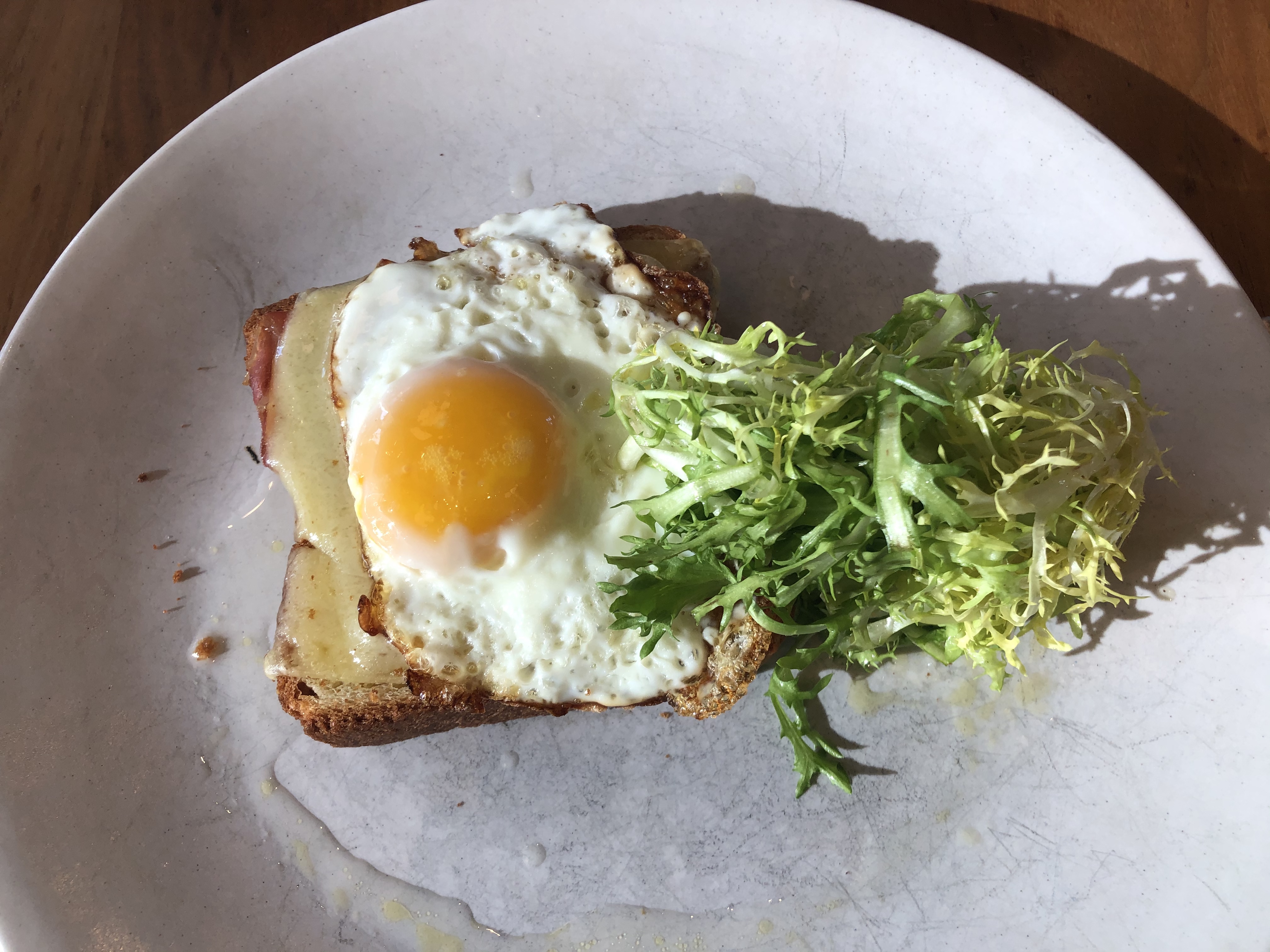 Croque madame on a plate with a pile of lettuce. 