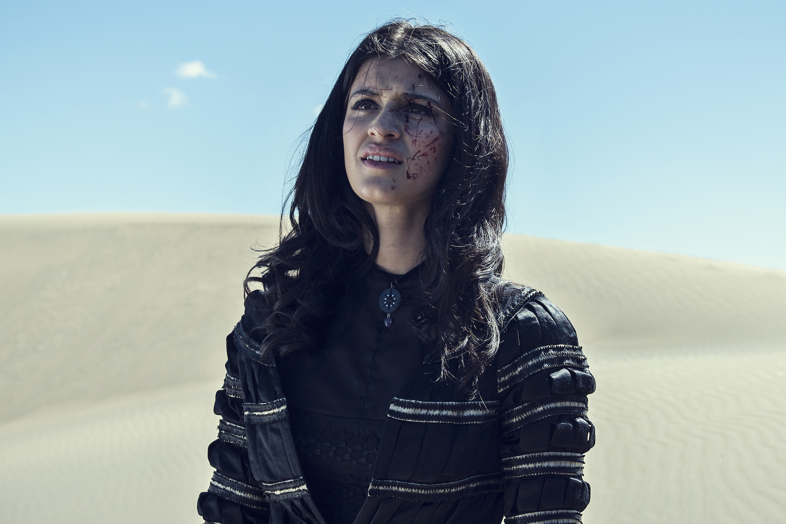 Yennefer stands in a desert, splattered with blood, in The Witcher