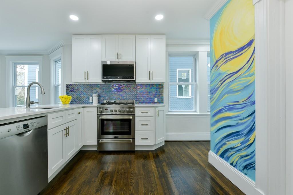 A kitchen with a long counter and a stylishly bright painted wall.