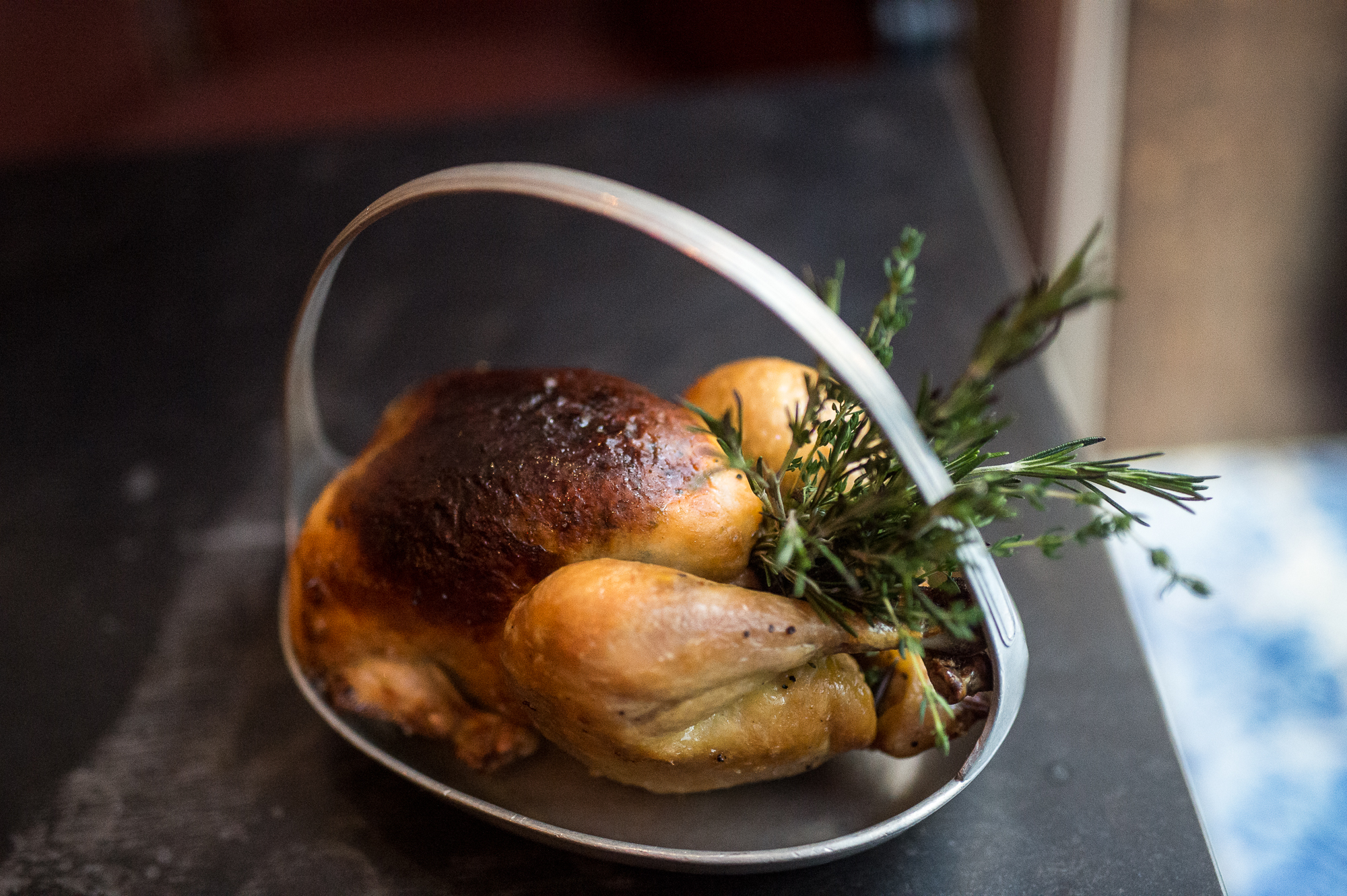 A roast chicken stuffed with herbs in a basket