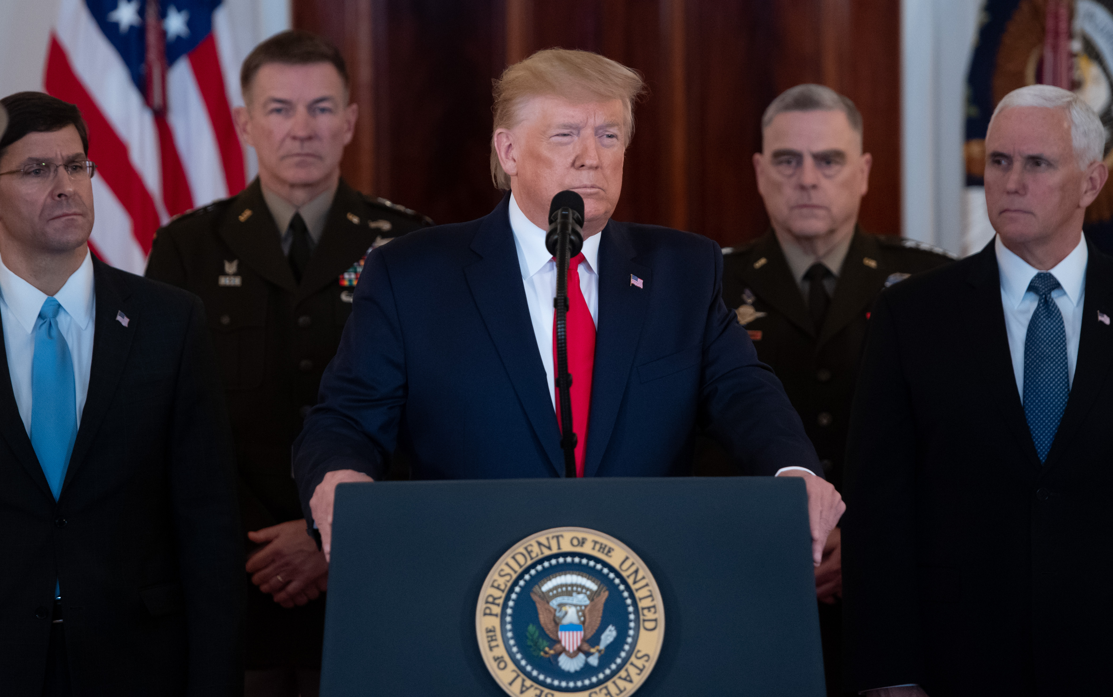 President Donald Trump stands at a podium backed by military commanders and Vice President Mike Pence.