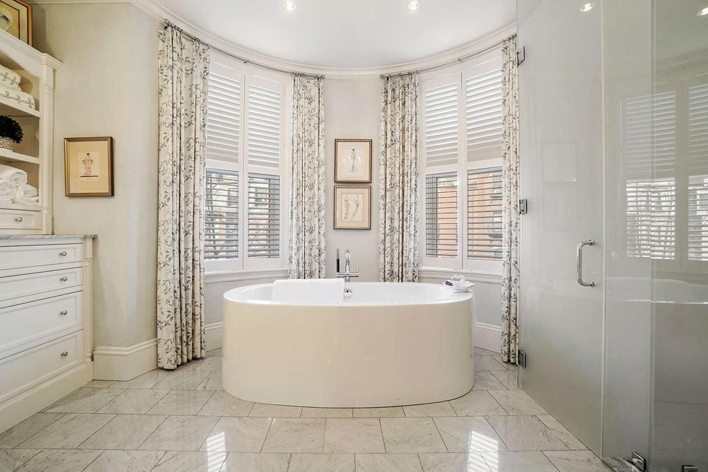 A spacious bathroom with a soaking tub prominently positioned in front of large windows.