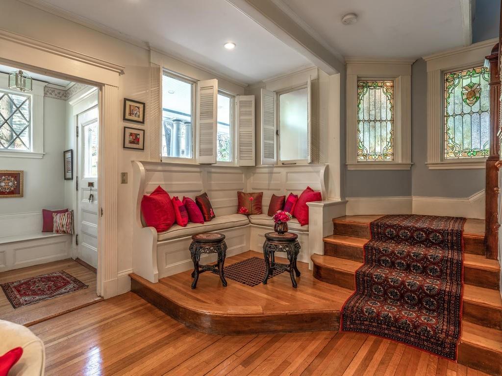 An entry foyer with a pillow-covered built-in bench next to a staircase.