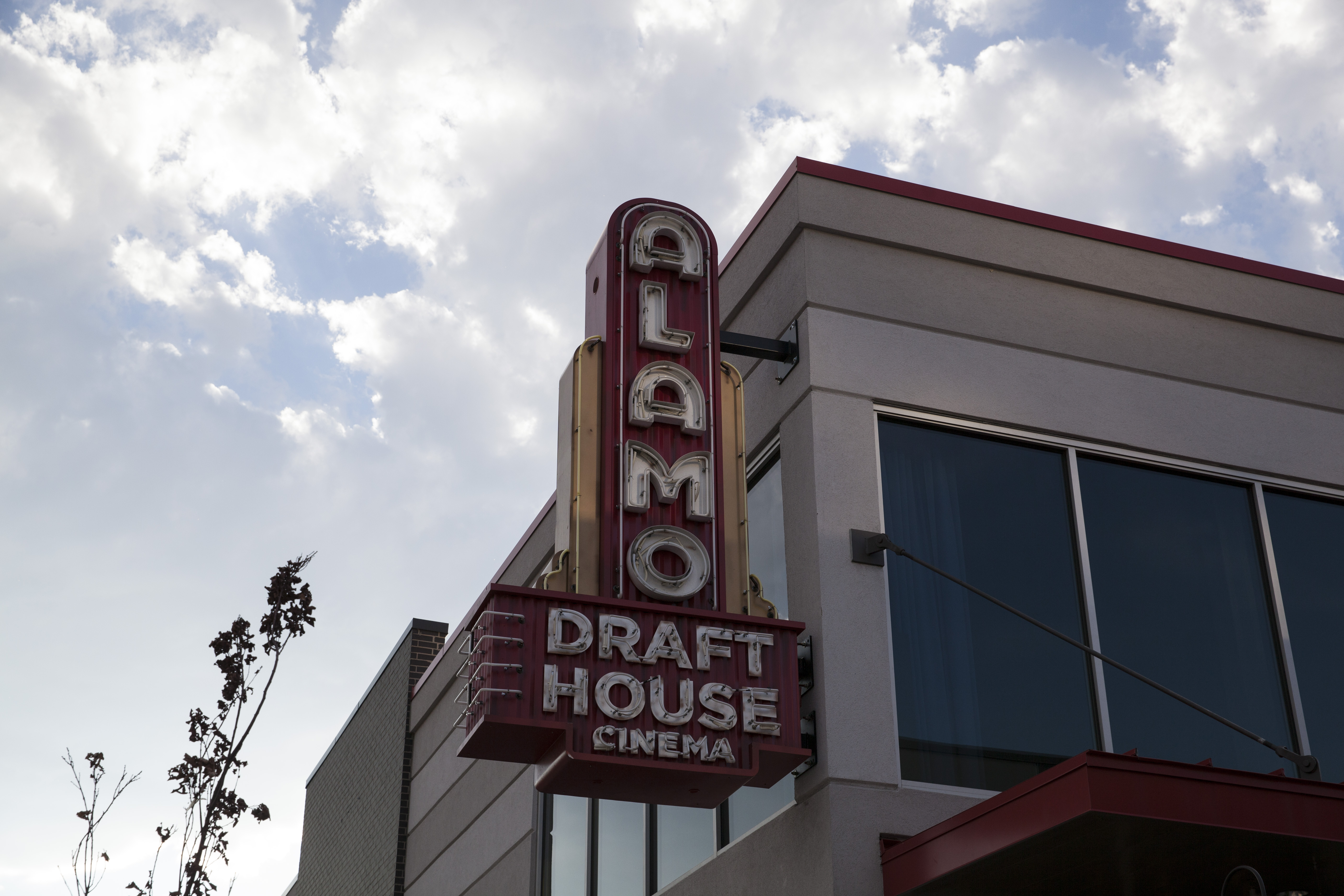 Red marquee on a building in the daytime that says Alamo Draft House Cinema. 