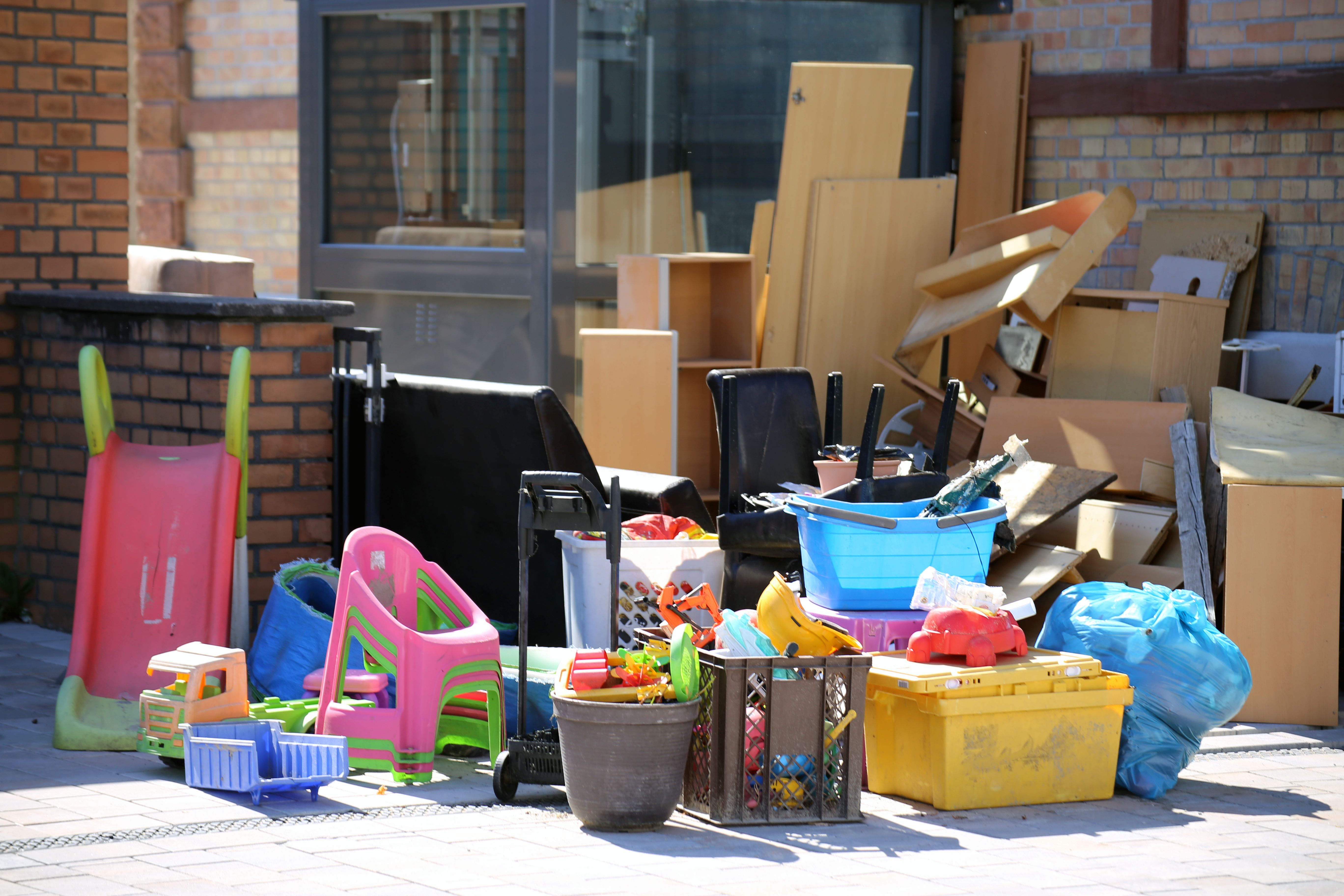 Boxes, toys, and other items on a sidewalk, in front of a building. 