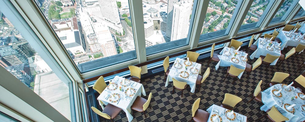 An aerial view of a restaurant dining room with Boston skyline views