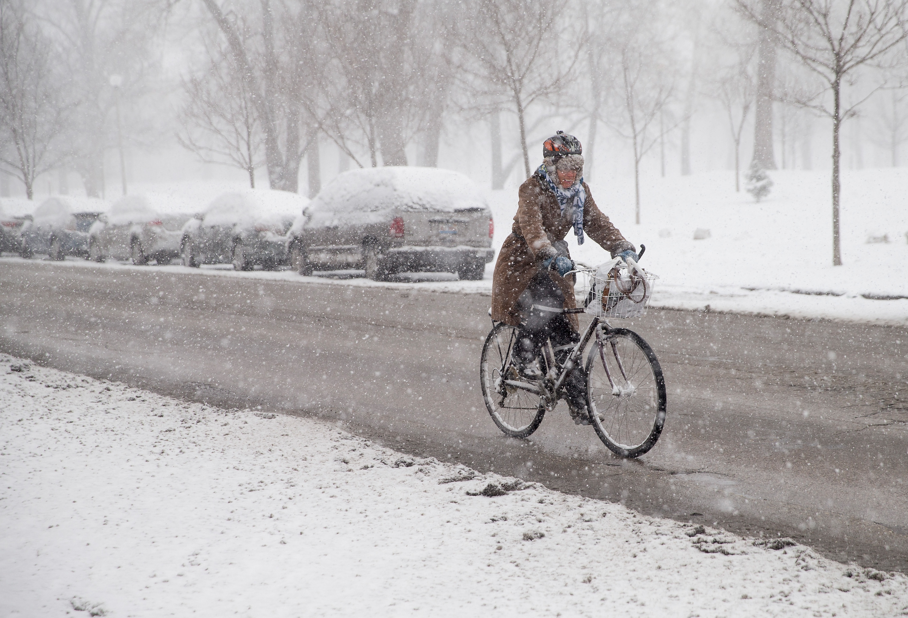 A woman on a bike rides through a snow street in Chicago.