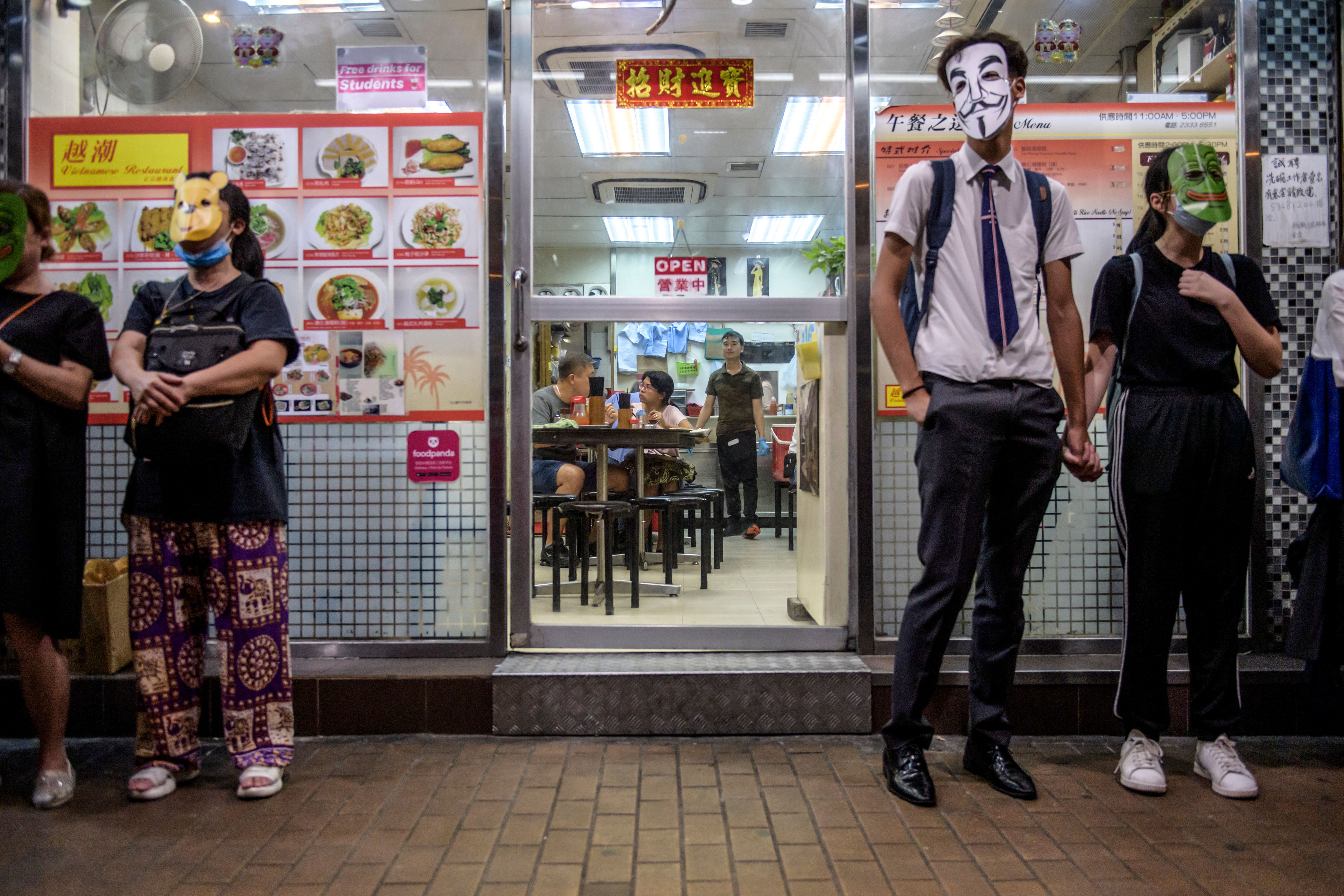 Masked protesters stand outside a restaurant