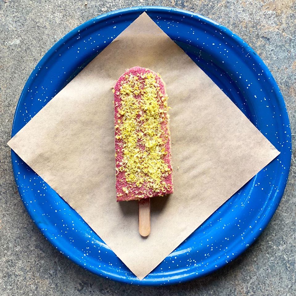 A pink paleta with shavings of something green on a blue plate