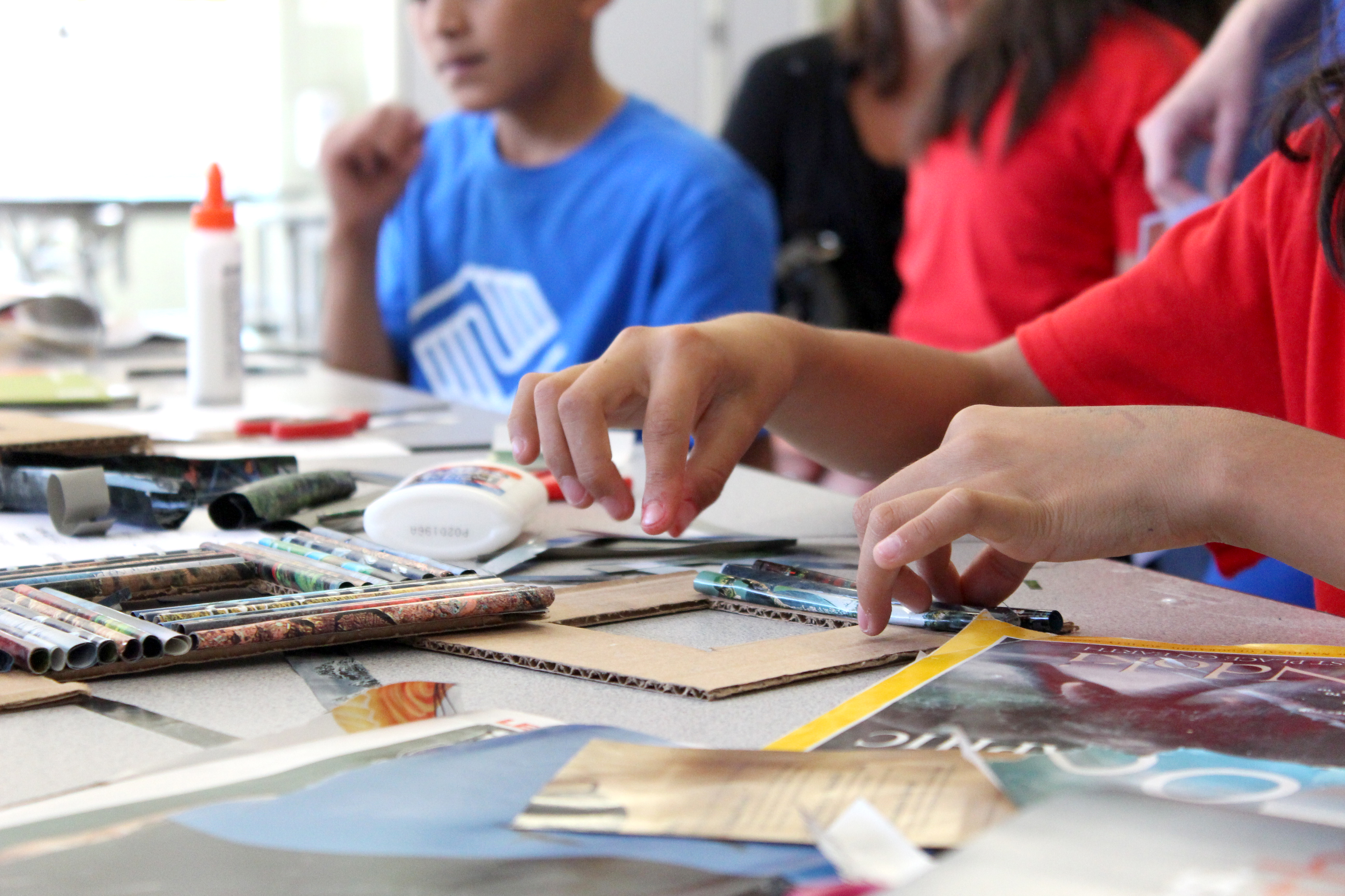 A student glues rolled up magazine pages onto a picture frame. The activity, offered by the Boys & Girls club, was all about creating "up-cyclced" art.
