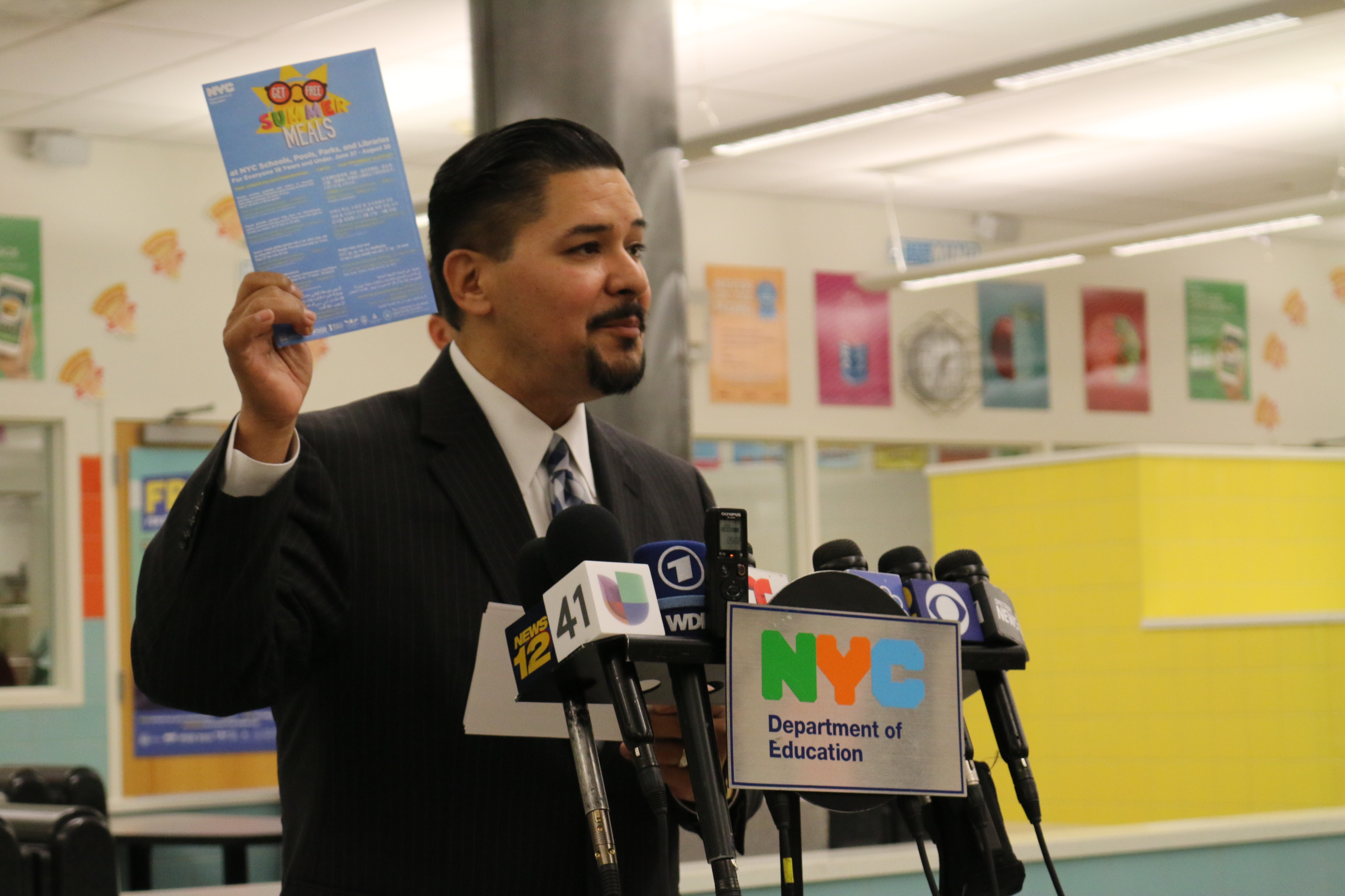 Chancellor Richard Carranza holds up a “summer meals” branded envelope at a launch event for the free summer meals program.