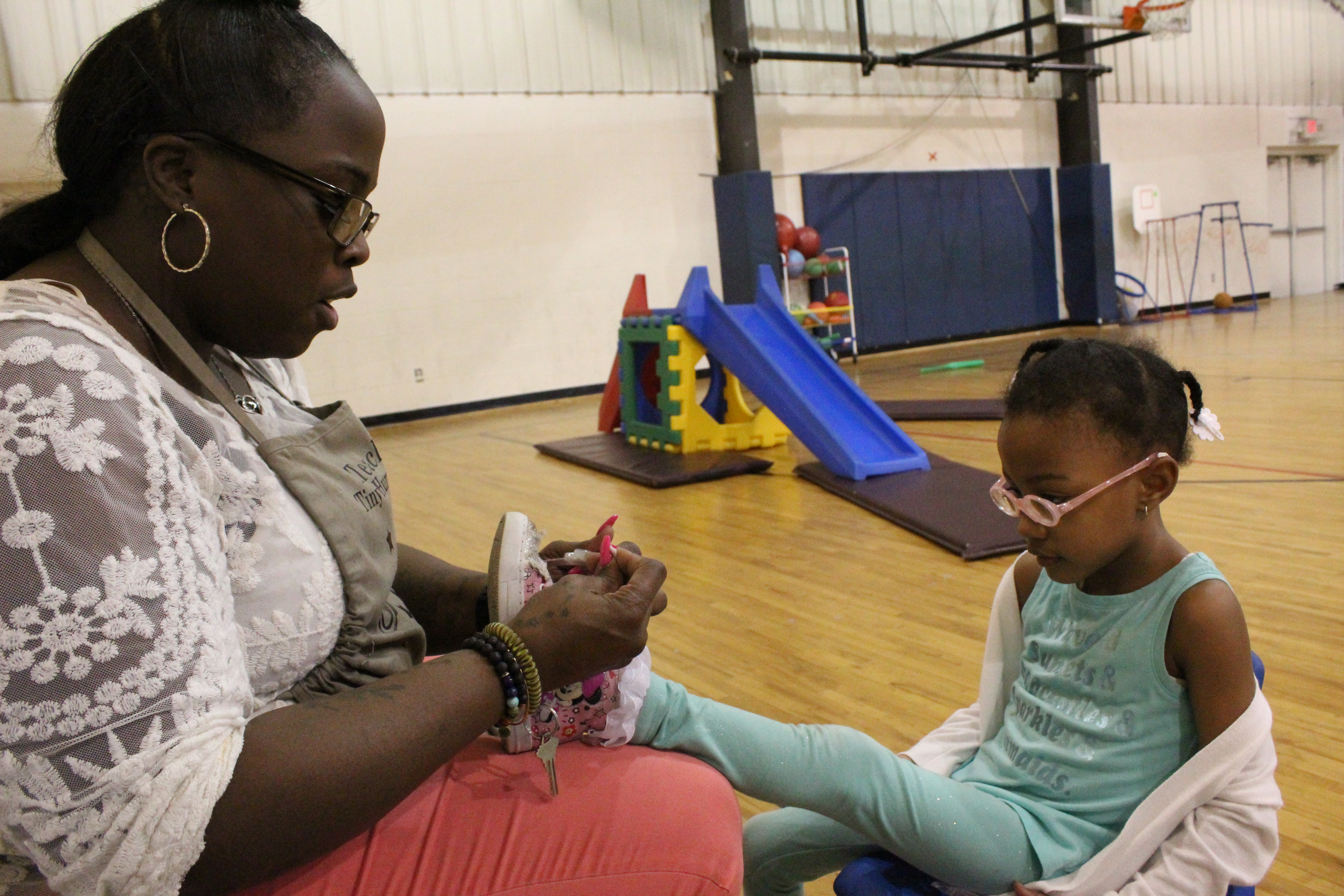 Cindy Lester, ties a shoelace during gym class at Children of the Rising Sun Empowerment Center in northwest Detroit.