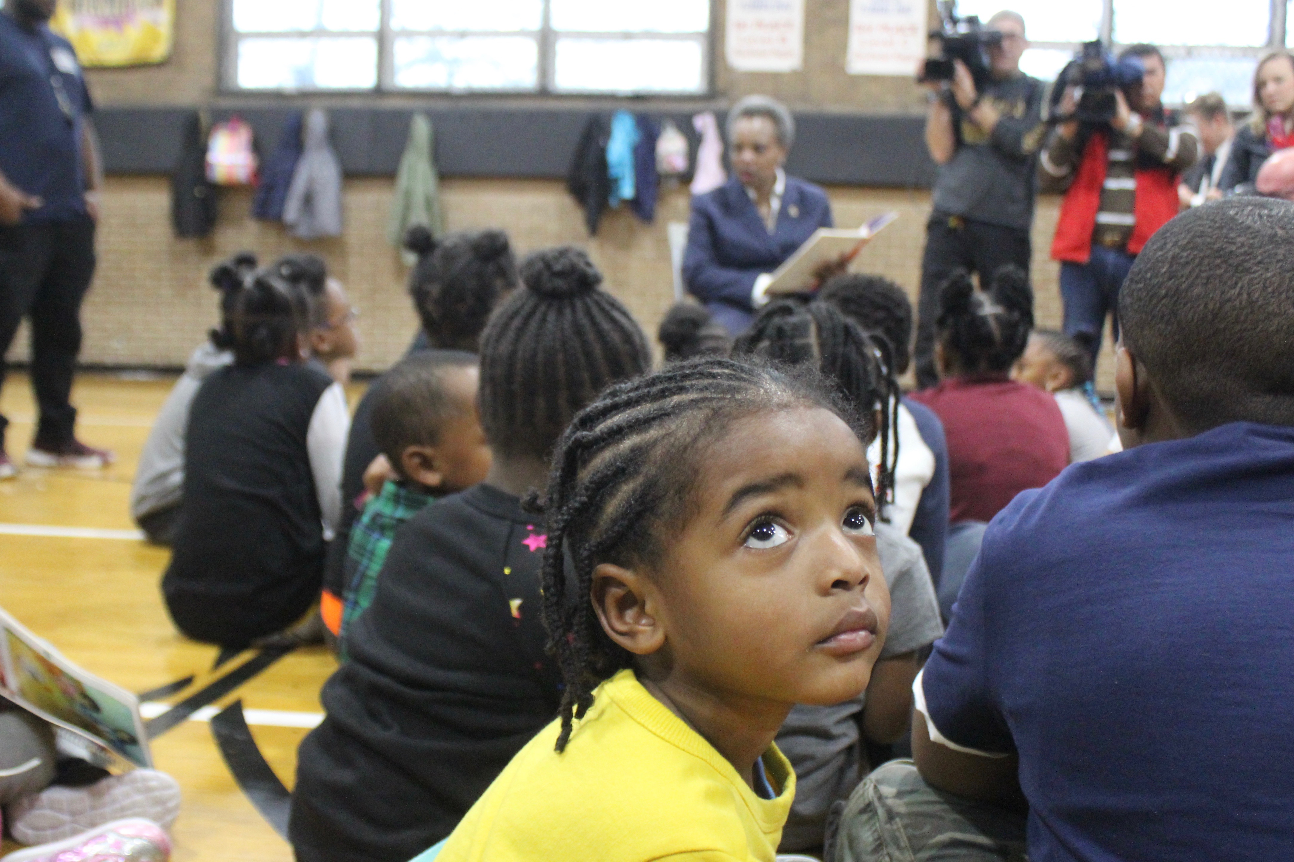 A student spending Wednesday morning at Kennicott Park in Kenwood glances up at media cameras as Mayor Lori Lightfoot reads a book aloud to a group of children during the 10th day of the teachers strike.