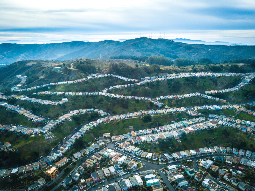 An aerial photo of tracts of homes crisscrossing a series of hills.