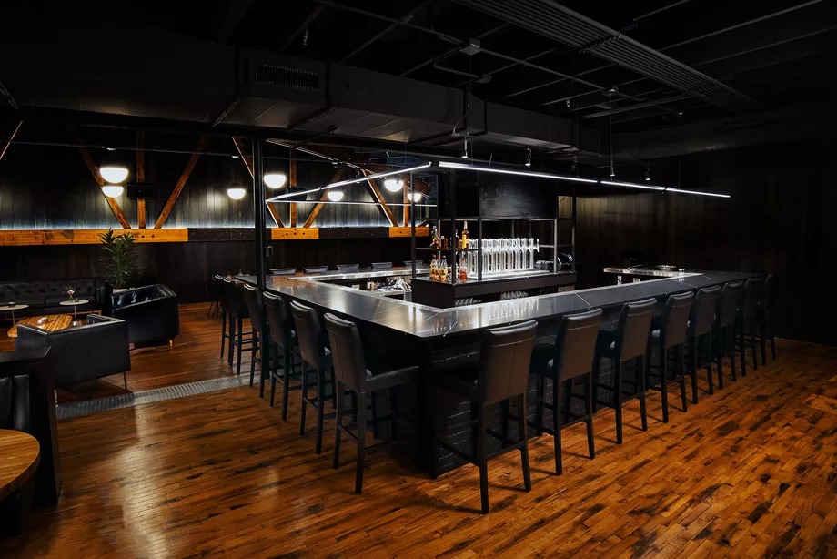 The dimly-lit bar space features a 22-seat Nero Marquina black marble bar.