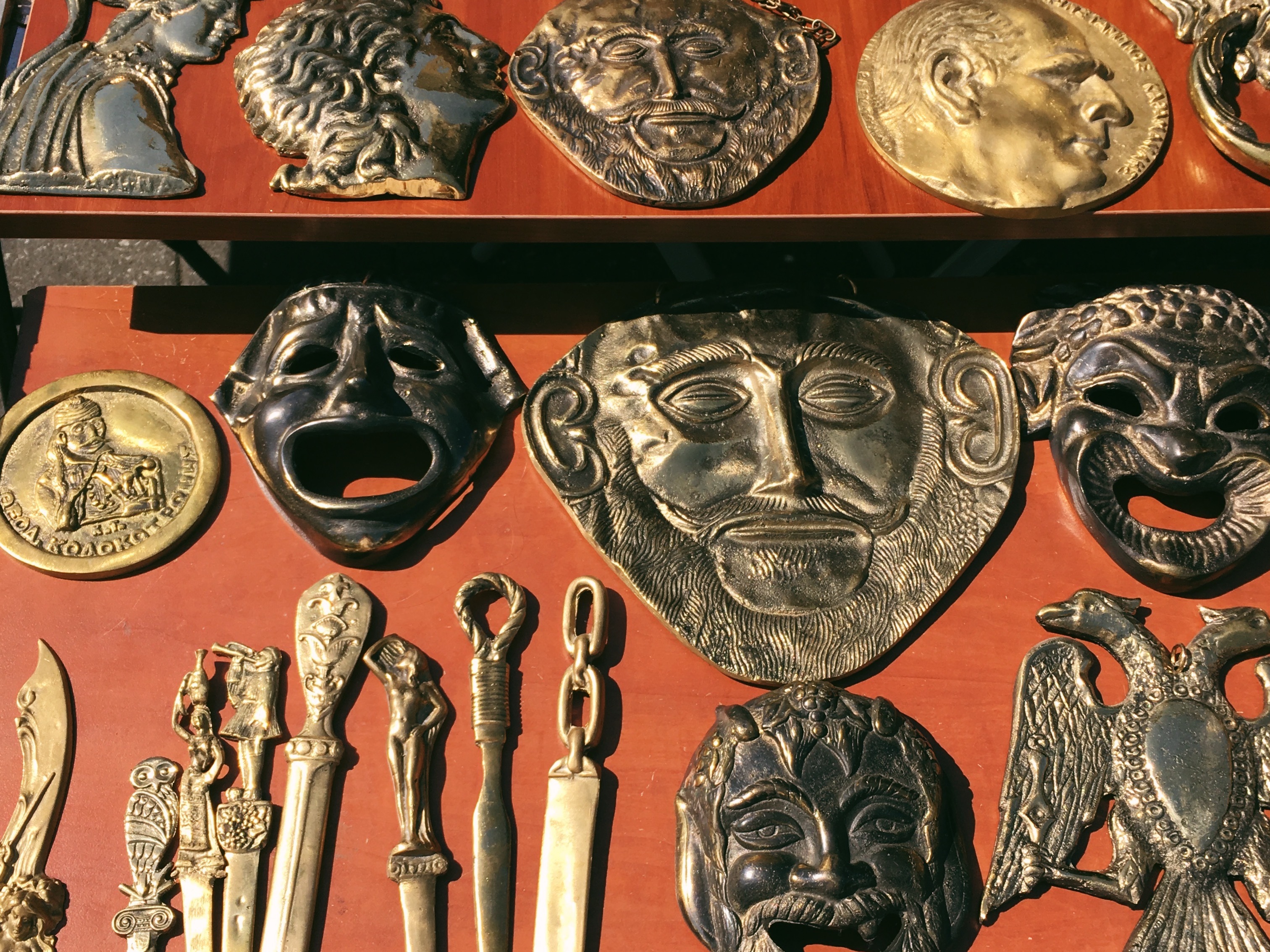 An array of copper masks are displayed on top of a red surface.