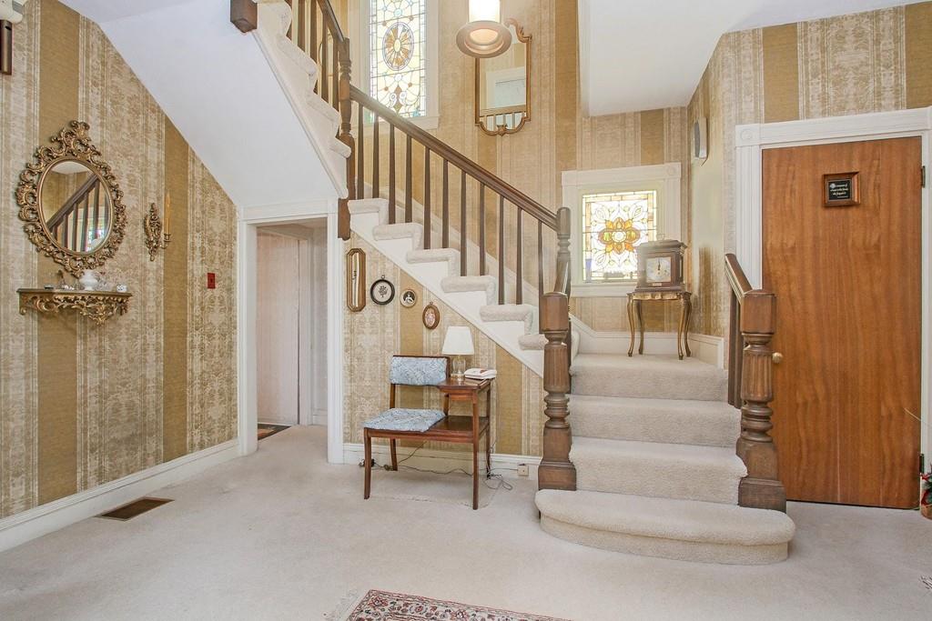 The plush entry foyer of a house with a staircase leading from it. 