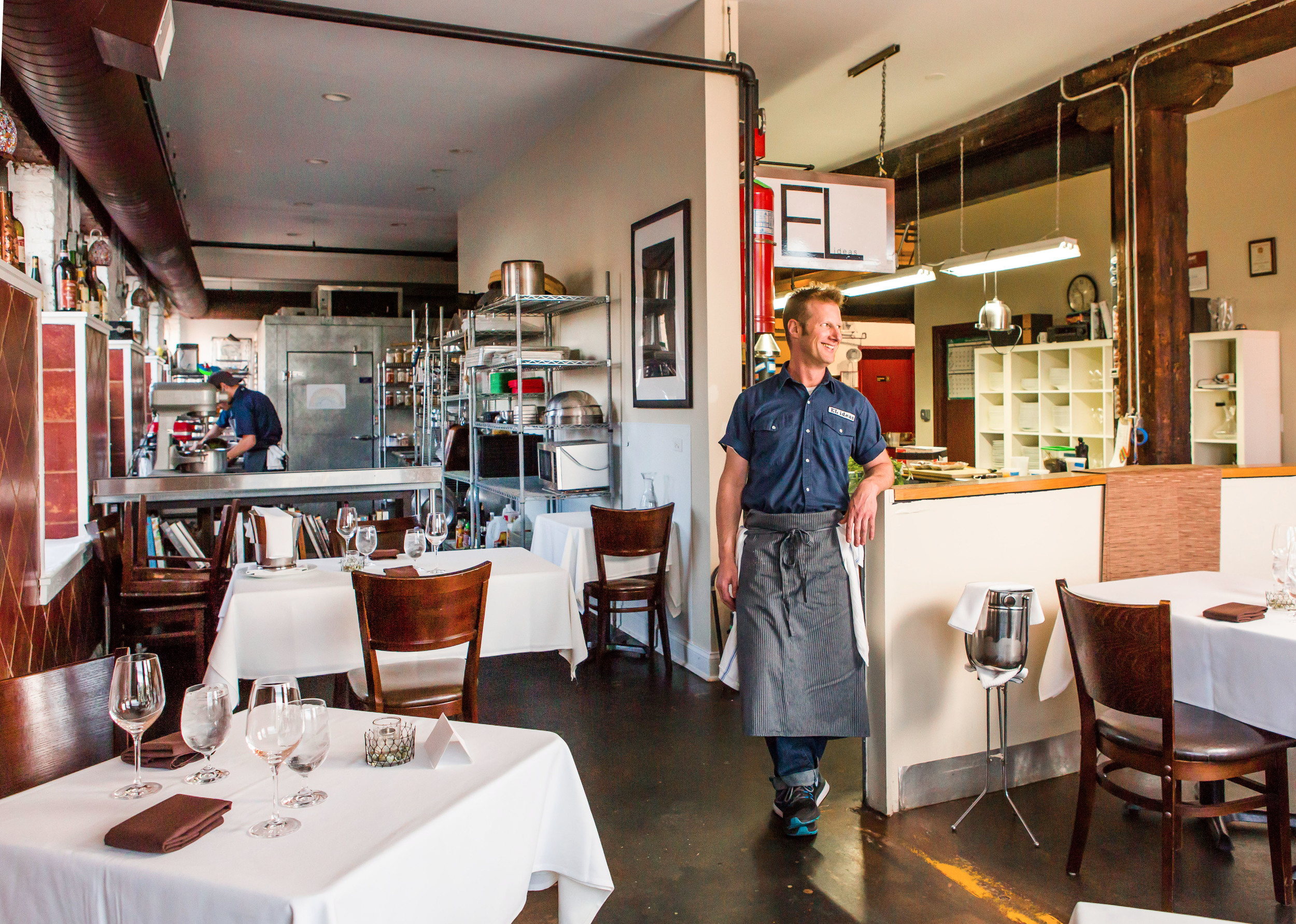 A white male chef stands inside a restaurant.