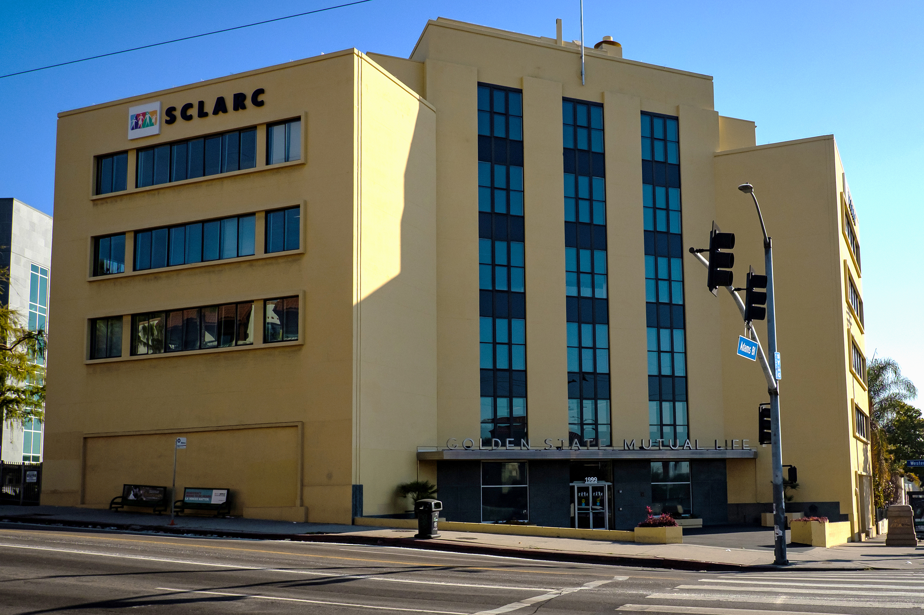 A yellow, 1940s-era mid-rise building at an intersection.